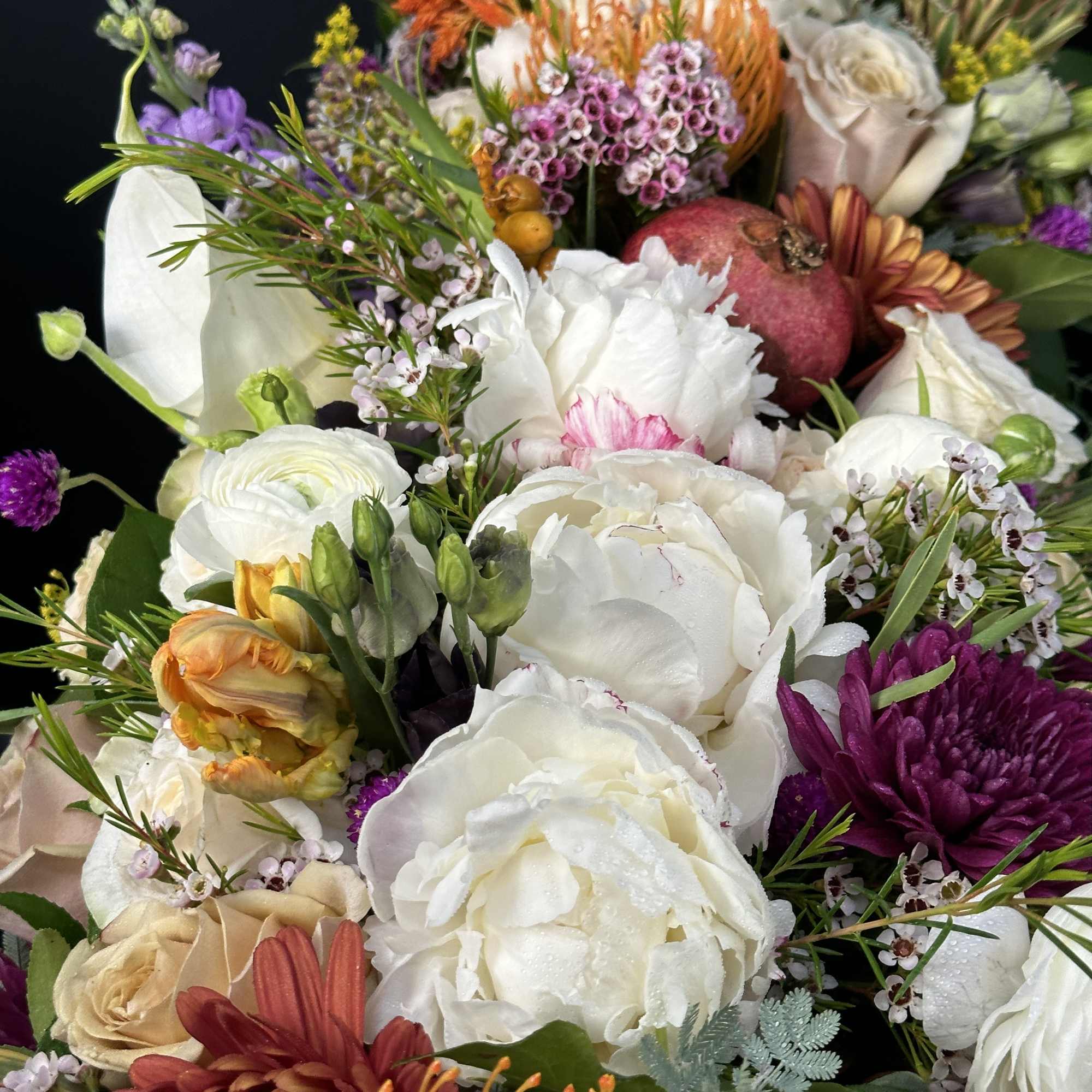 Mixed floral arrangement with white, purple, orange, and cream blooms