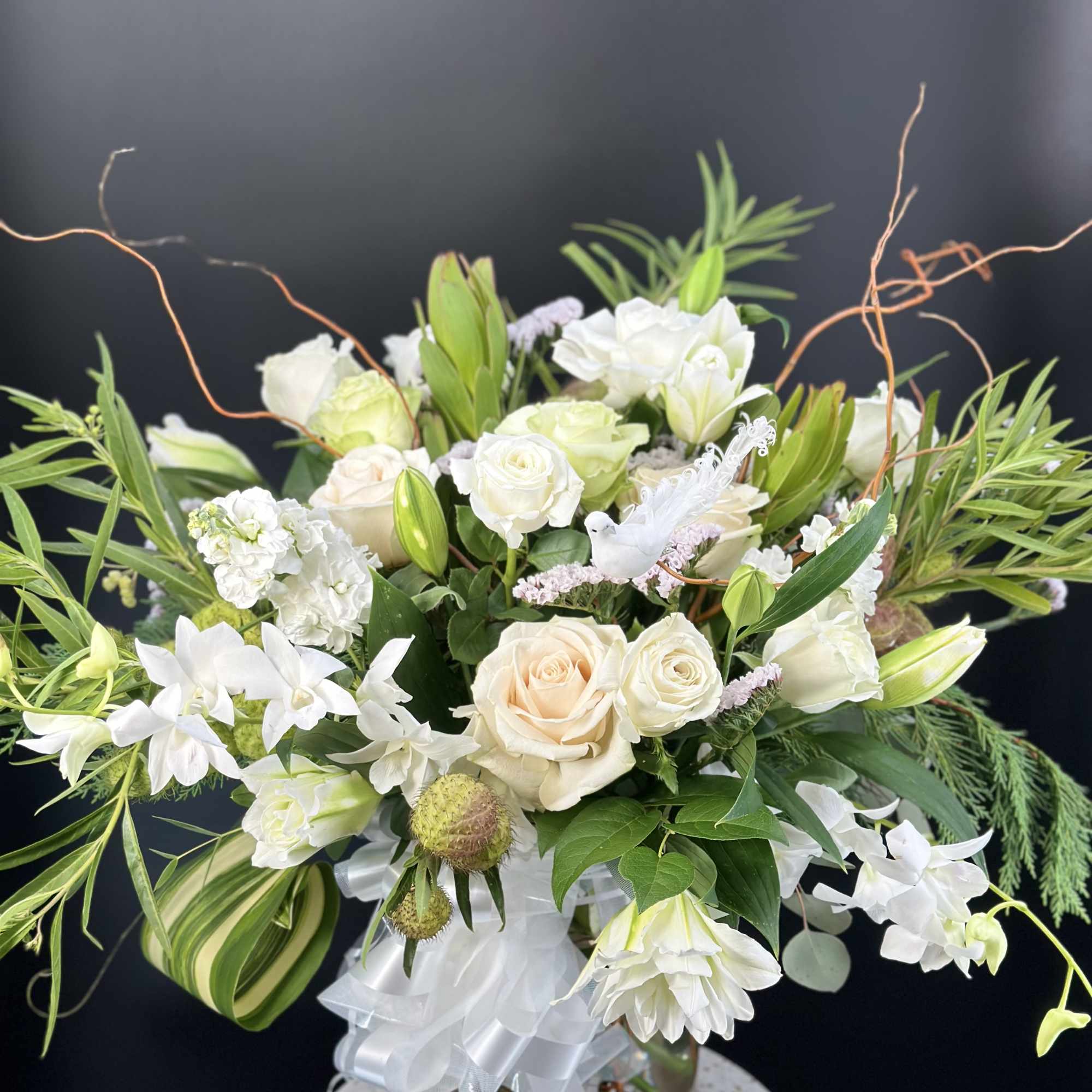White and cream floral arrangement in a glass vase with ribbon