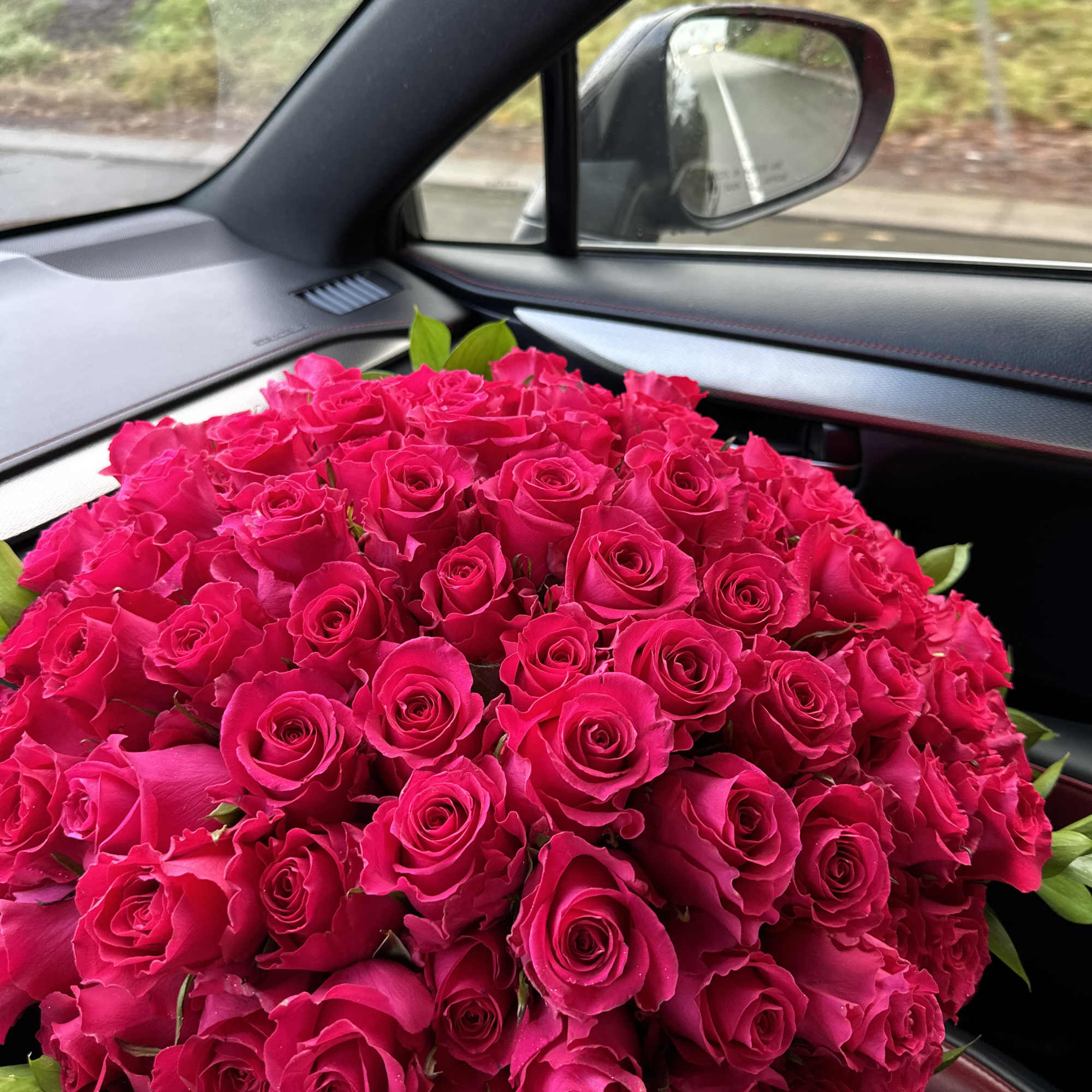 Large bouquet of bright pink roses in a car seat