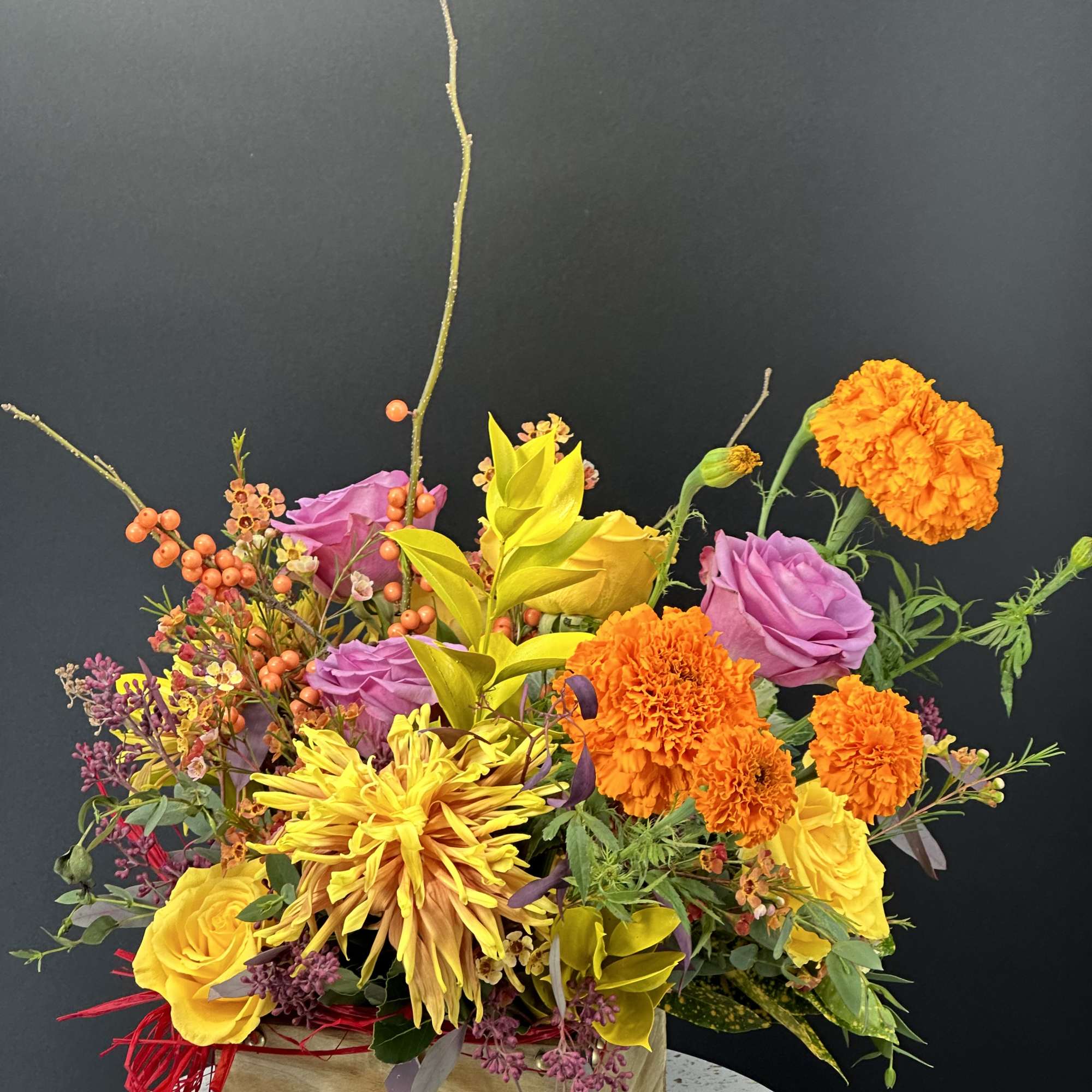 Bright mixed bouquet in a wooden box with yellow, purple, and orange flowers