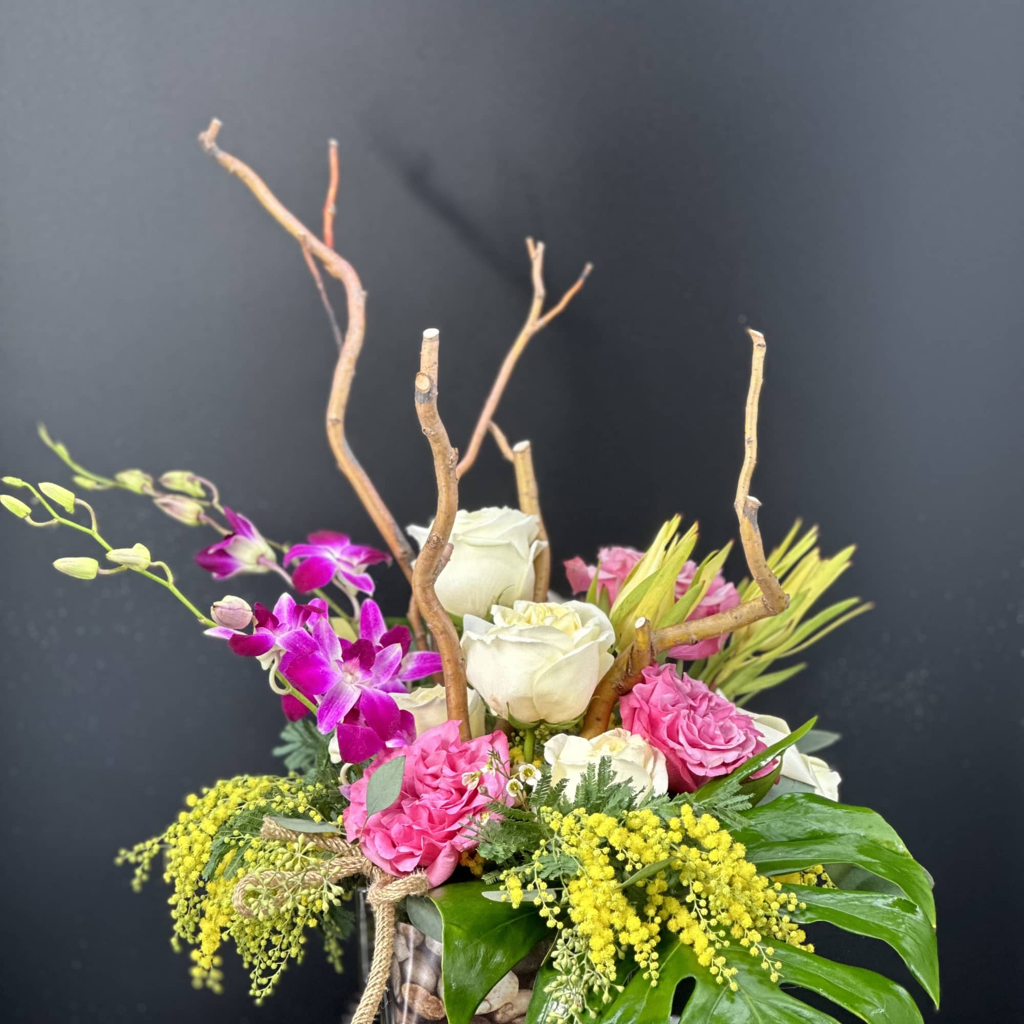 Pink and white floral arrangement in a glass vase with branches