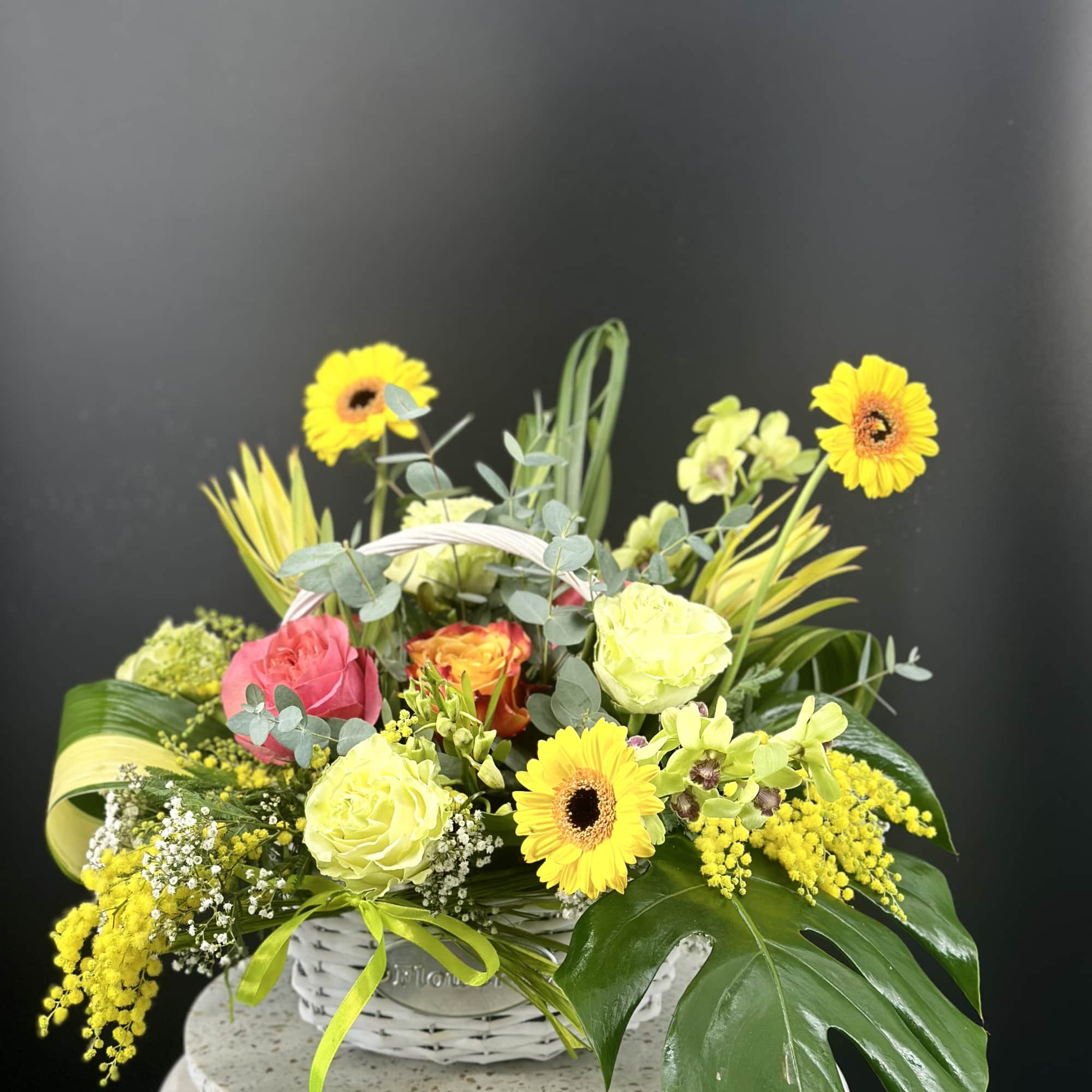 Basket arrangement of yellow gerberas and roses with mixed greenery
