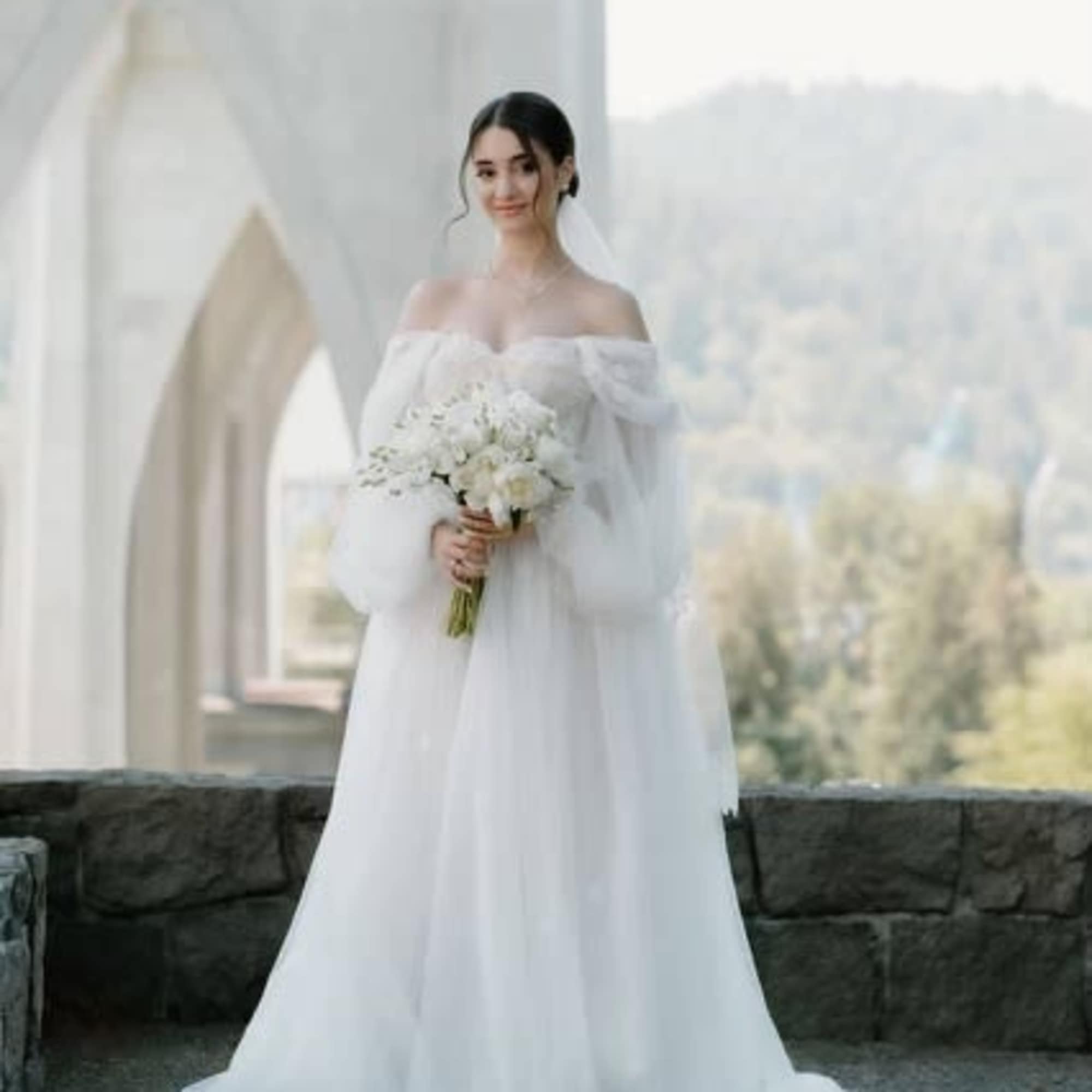Bride in a white gown holding a white bouquet, photo 14 of 15