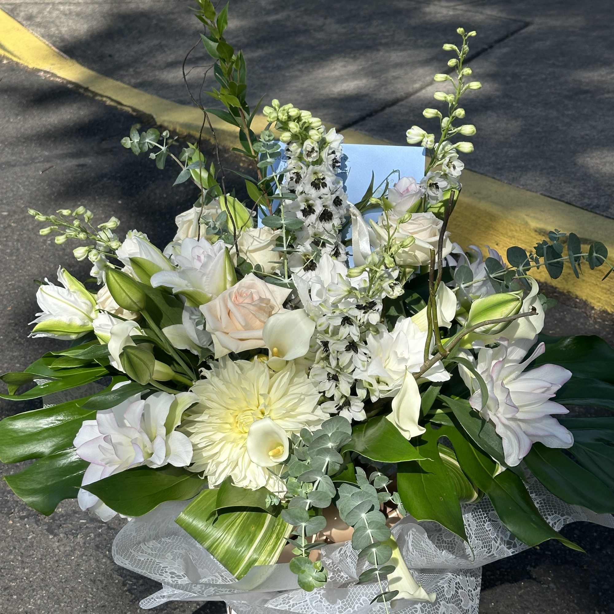 White floral arrangement with lilies, roses, and a large chrysanthemum