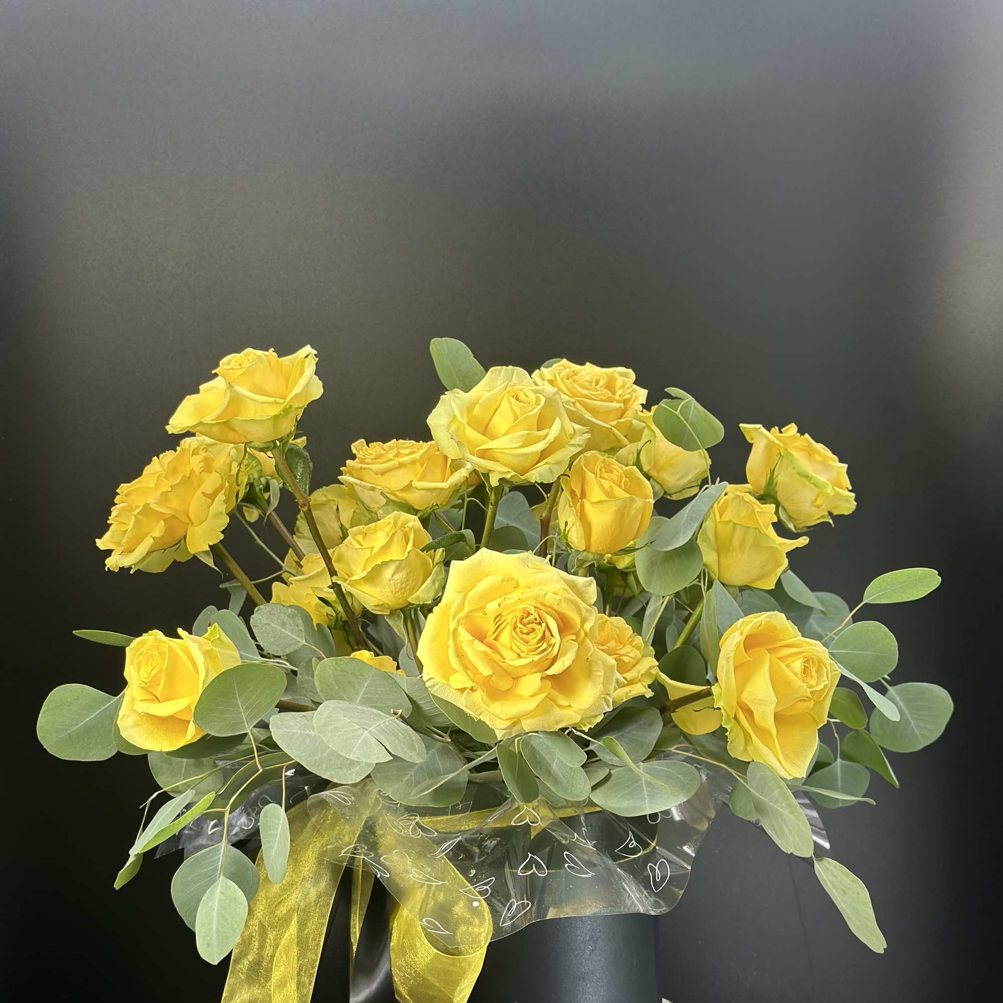 Yellow roses in a black hatbox with a yellow ribbon