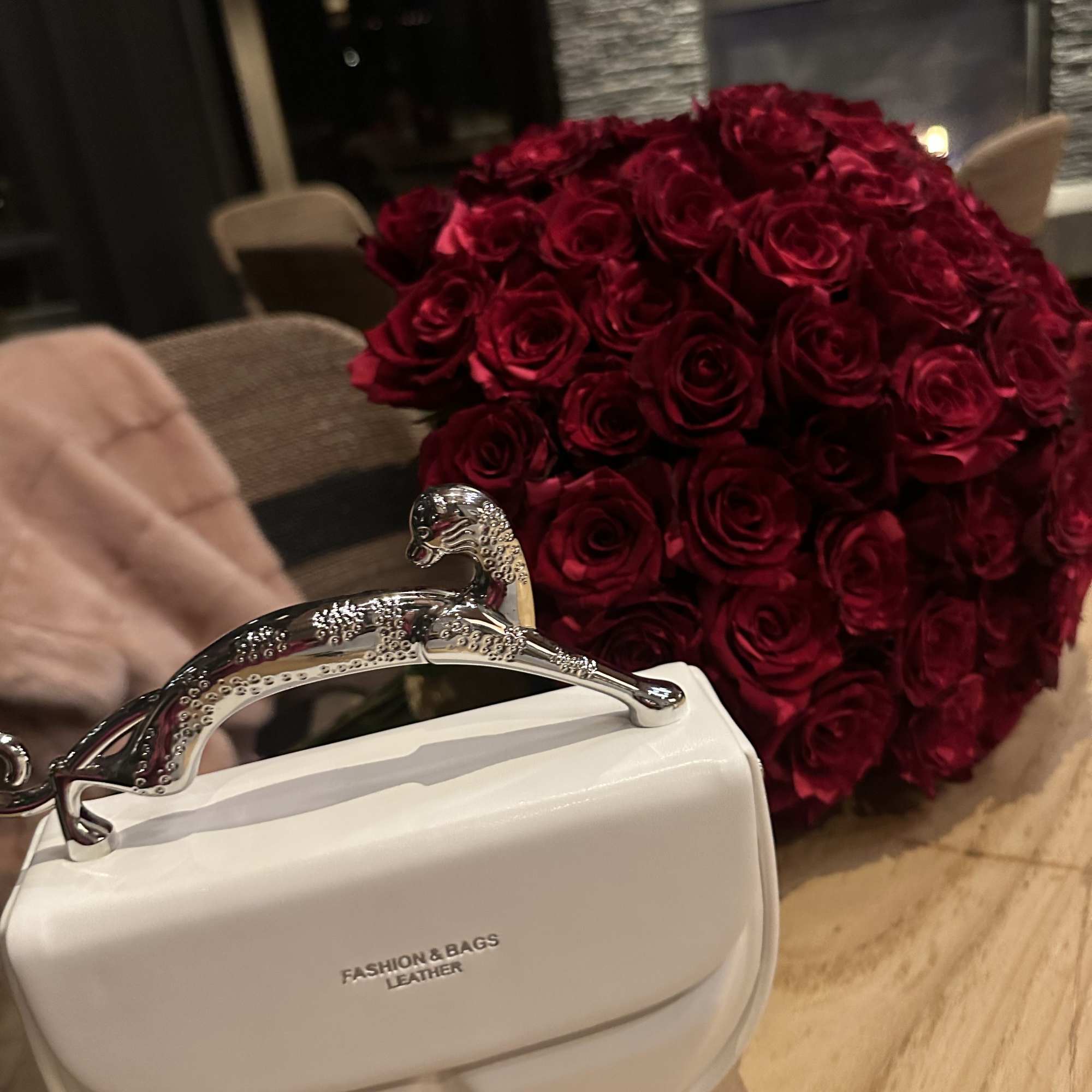 Large bouquet of deep red roses beside a white handbag