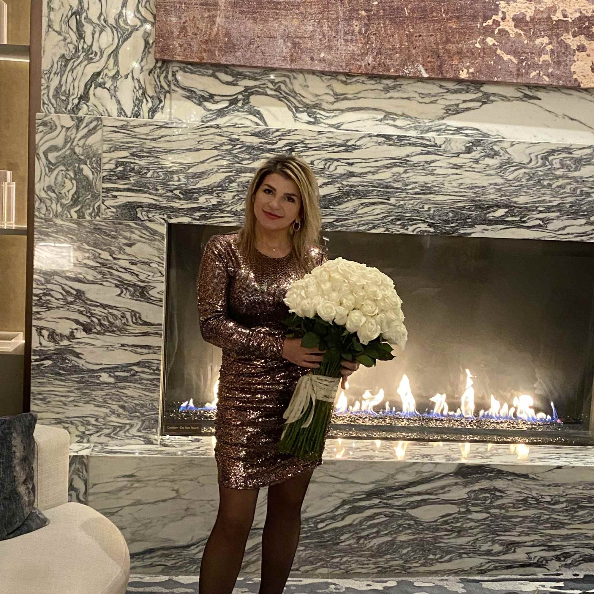Woman holding a large bouquet of white roses in front of a fireplace, photo 5 of 19