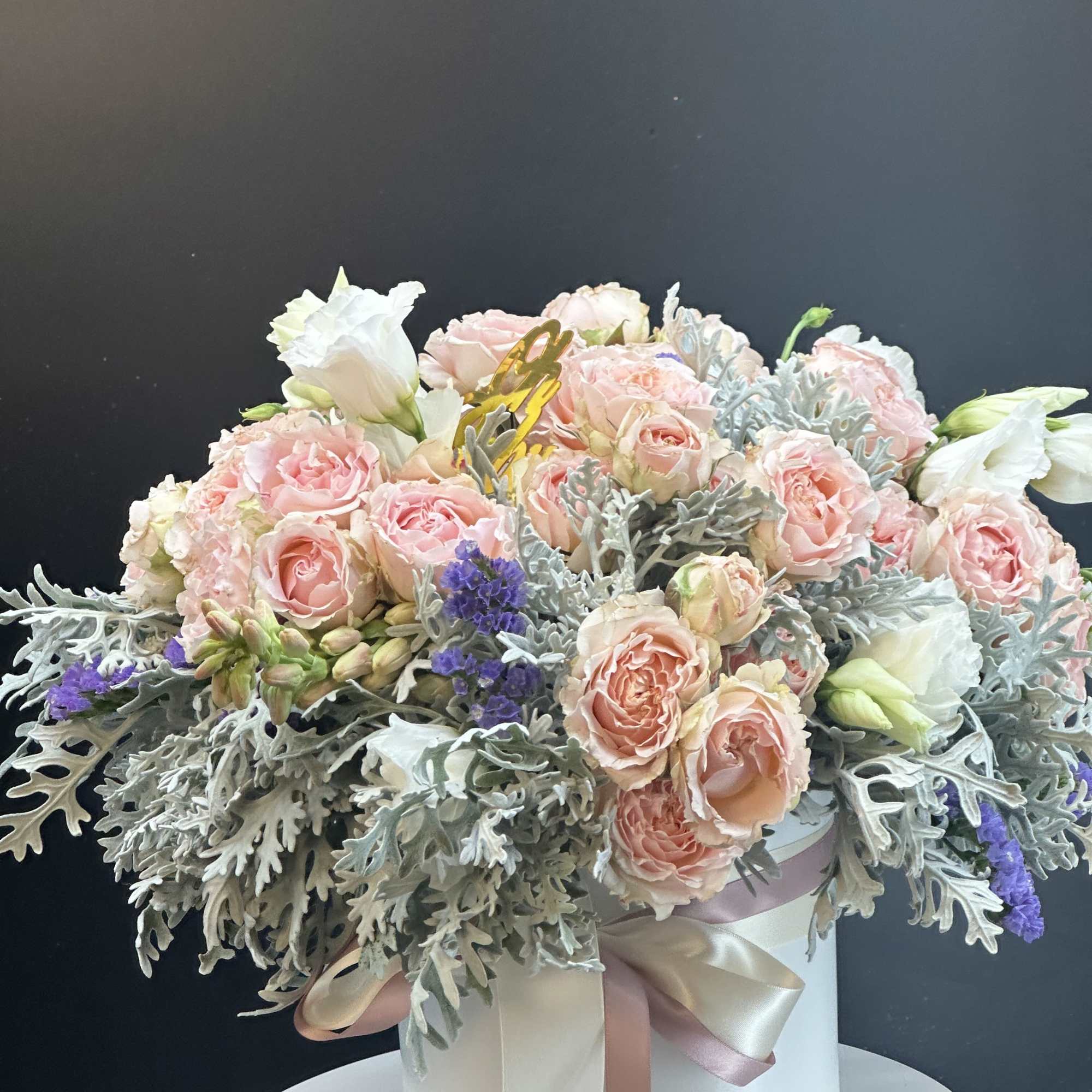 Blush roses and white lisianthus in a white hatbox with ribbon