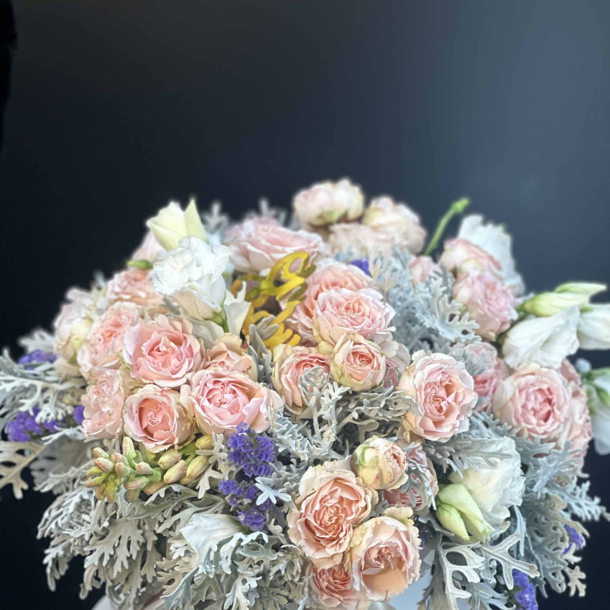Bouquet of blush pink roses with pale blue-gray foliage in a white box
