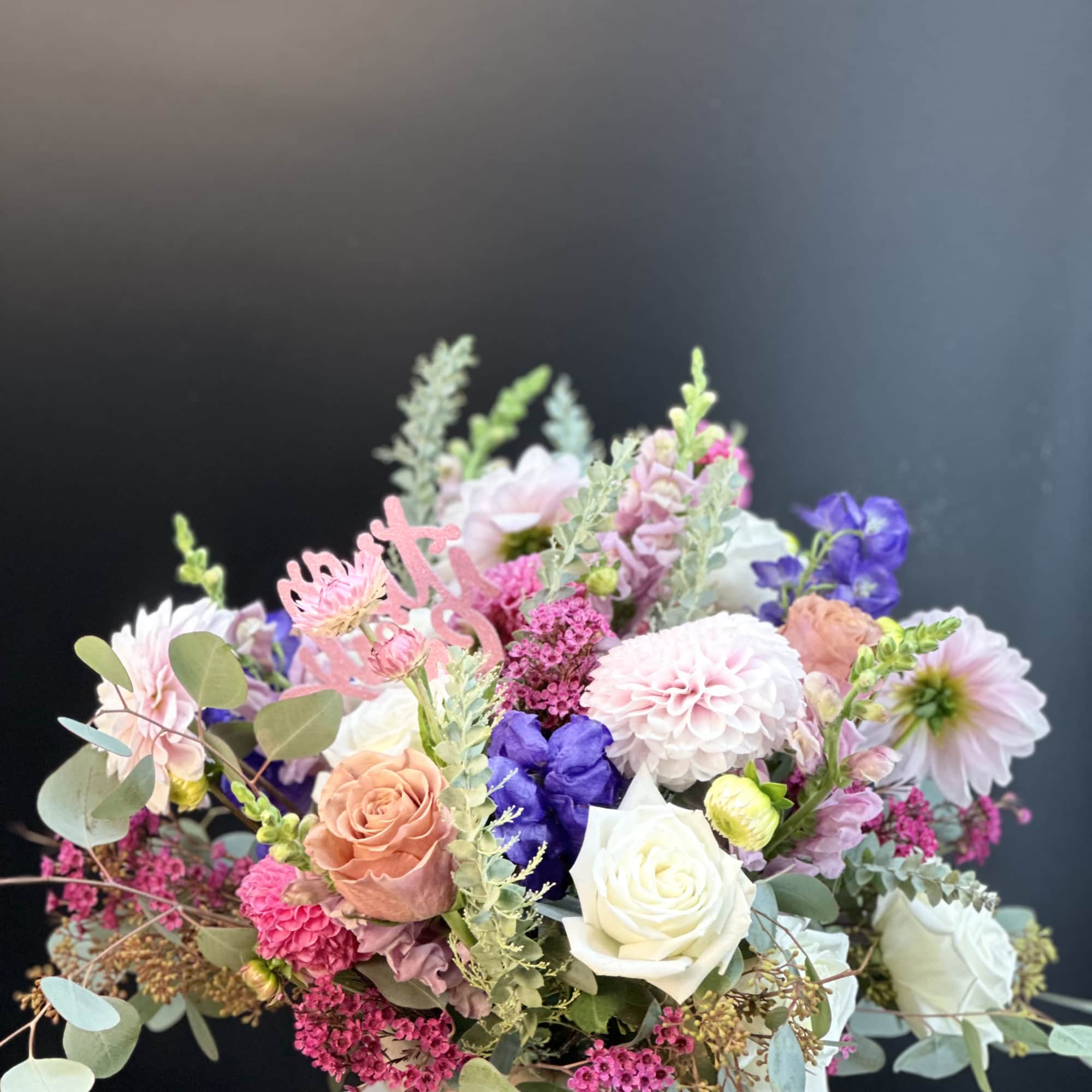 Mixed bouquet of pastel roses, dahlias, and purple blooms in a vase