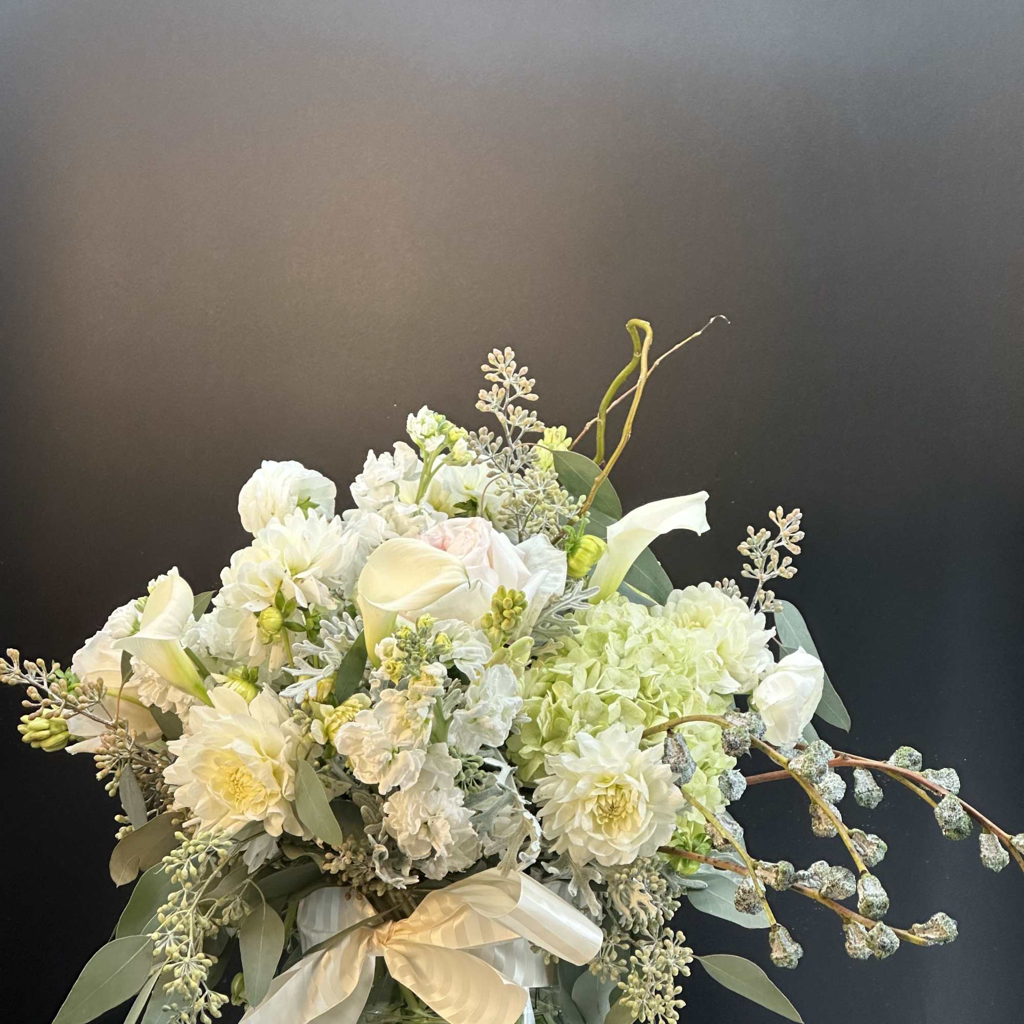 White floral arrangement in a glass vase with a satin ribbon