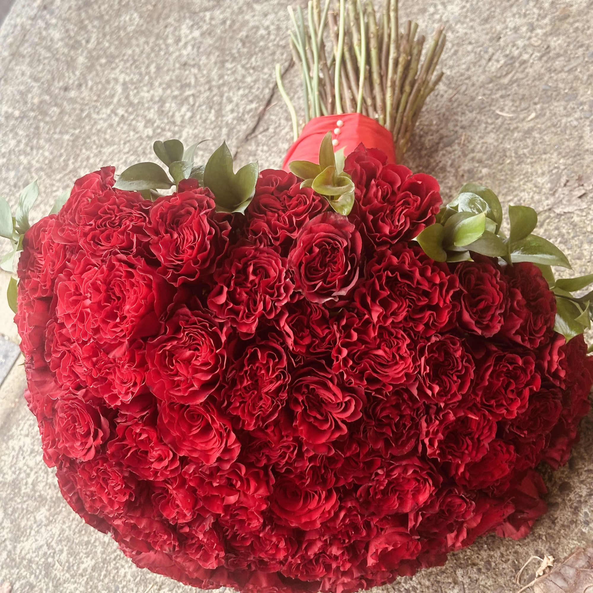 Heart-shaped bouquet of red roses with green accents