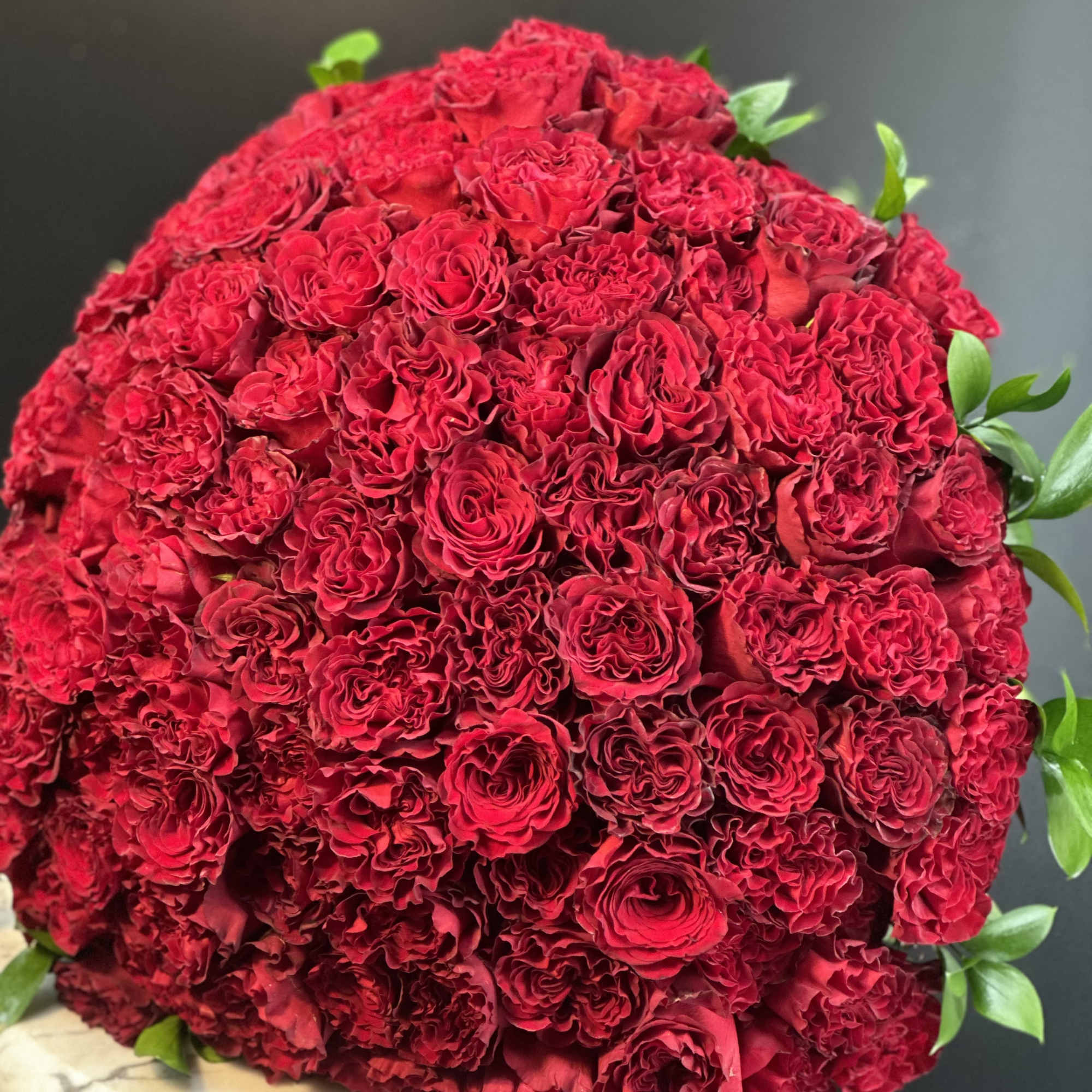 Large dome bouquet of red roses with a few green leaves
