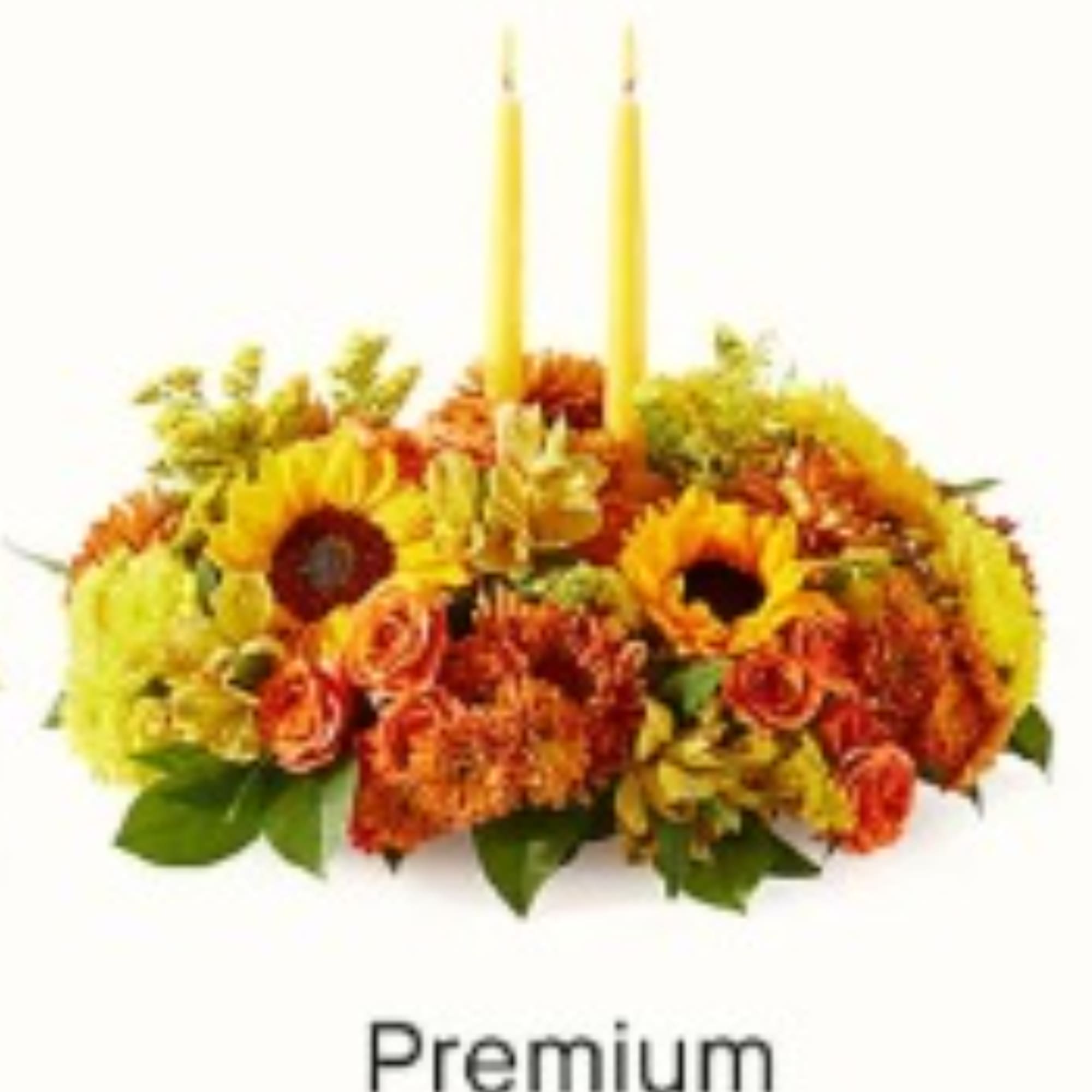 Autumn floral centerpiece with sunflowers and orange blooms around two yellow candles