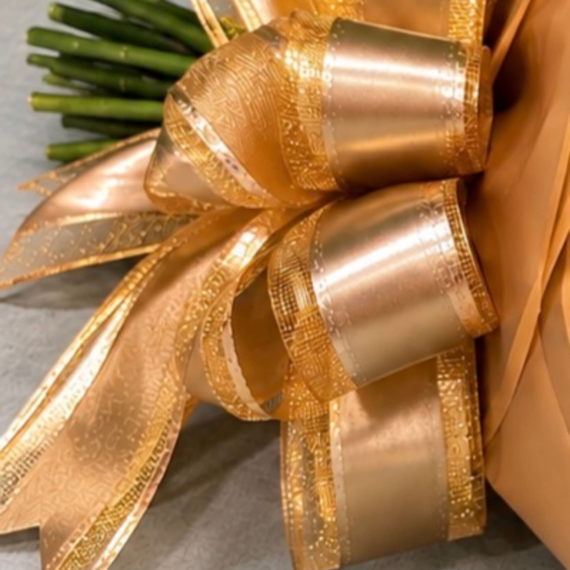 Gold ribbon bow with green flower stems beside it
