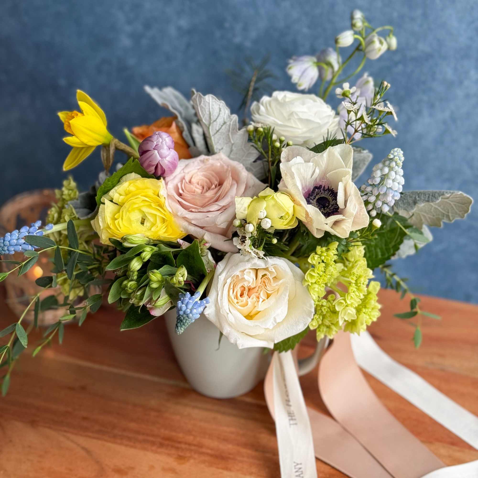 Mixed bouquet in a white mug-style vase with pastel roses and anemones