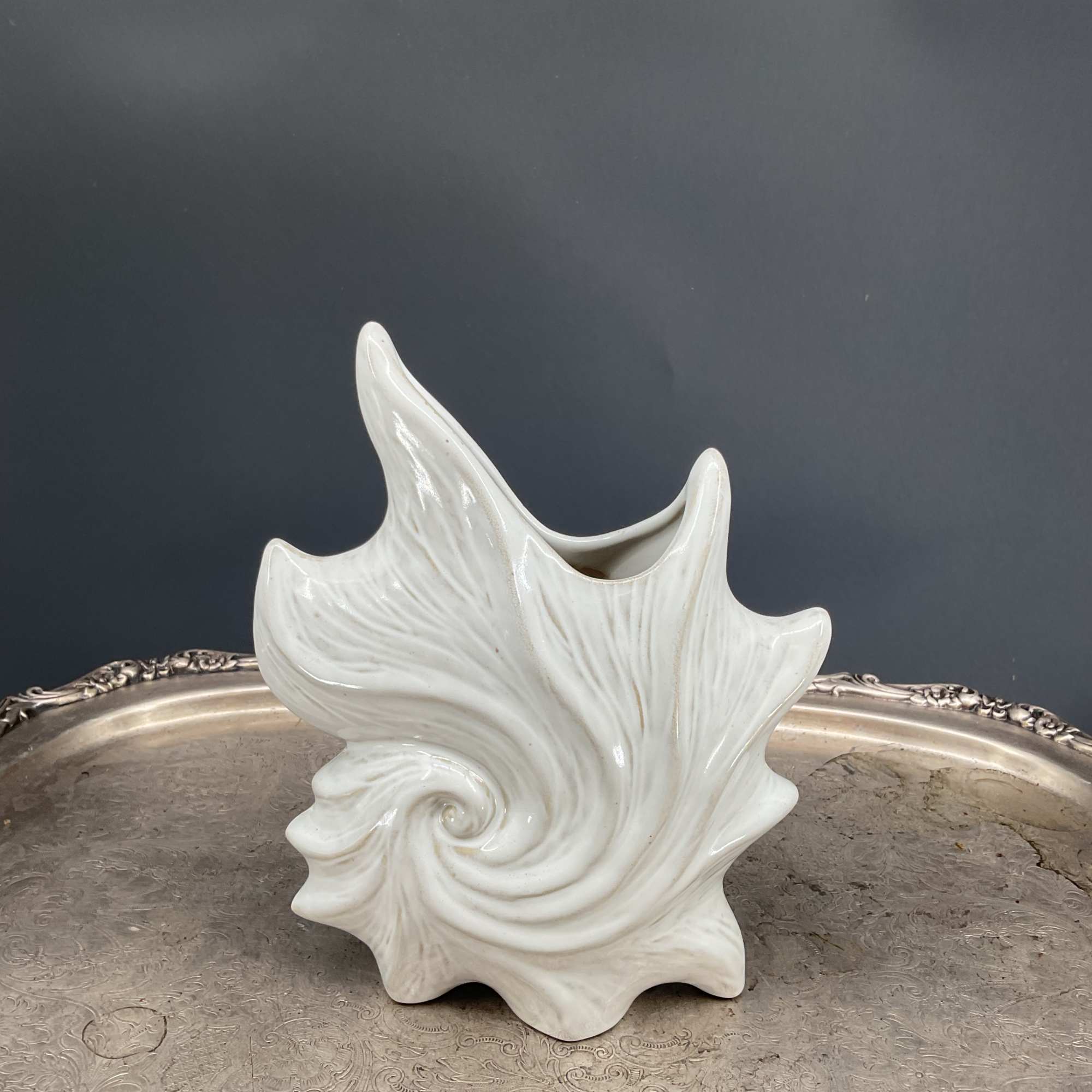 White ceramic shell-shaped vase on a silver tray