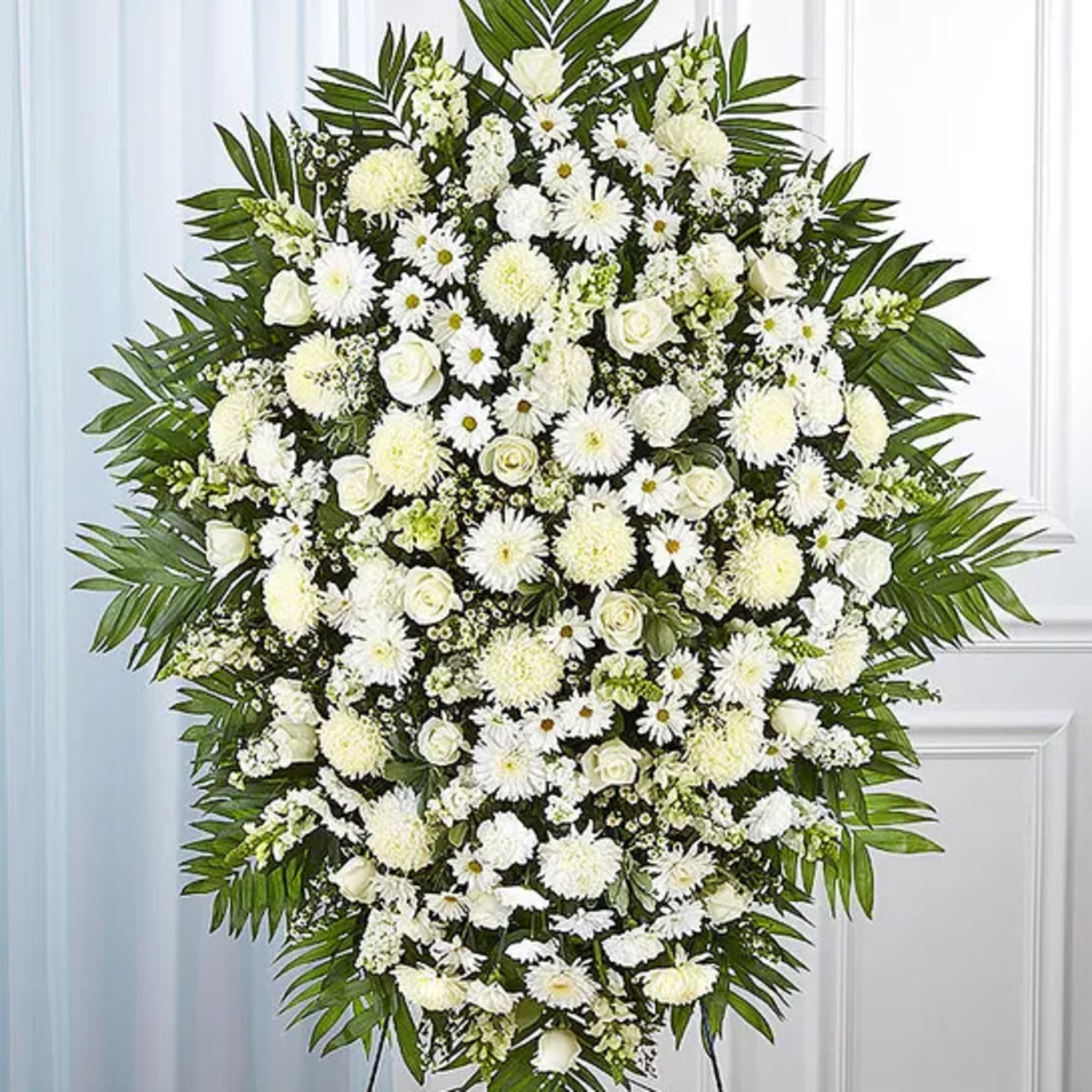 Large white funeral spray with roses and daisies on a stand