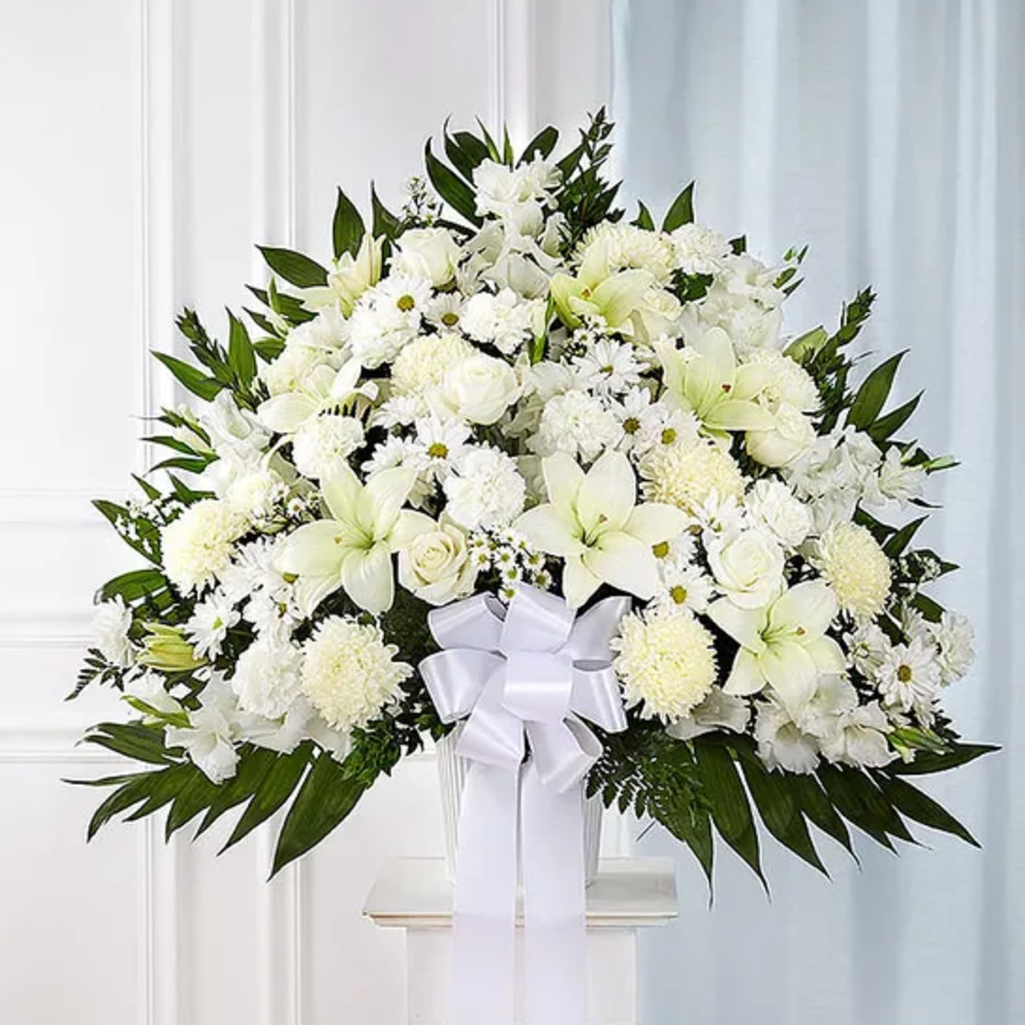 Large white floral arrangement with lilies and roses in a vase