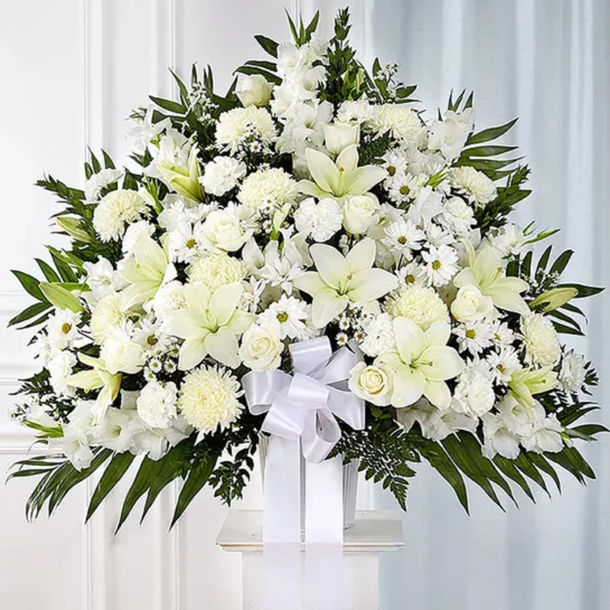 Large white floral spray with a ribbon on a pedestal stand