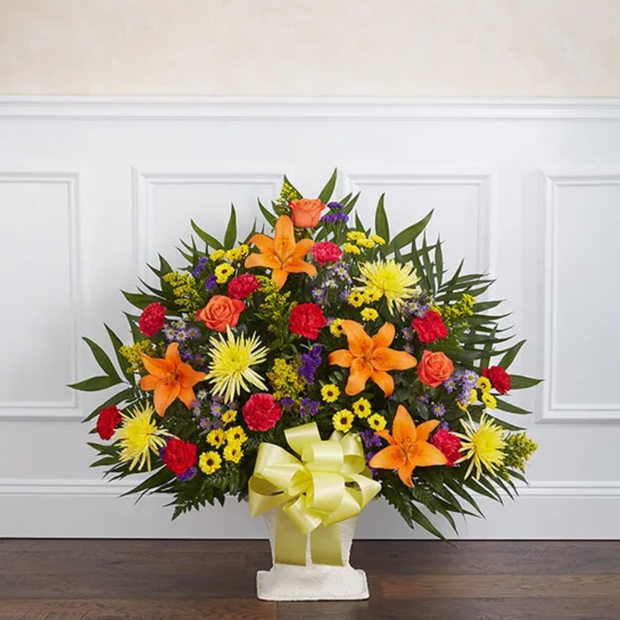 Colorful floral spray in a white basket with a yellow bow