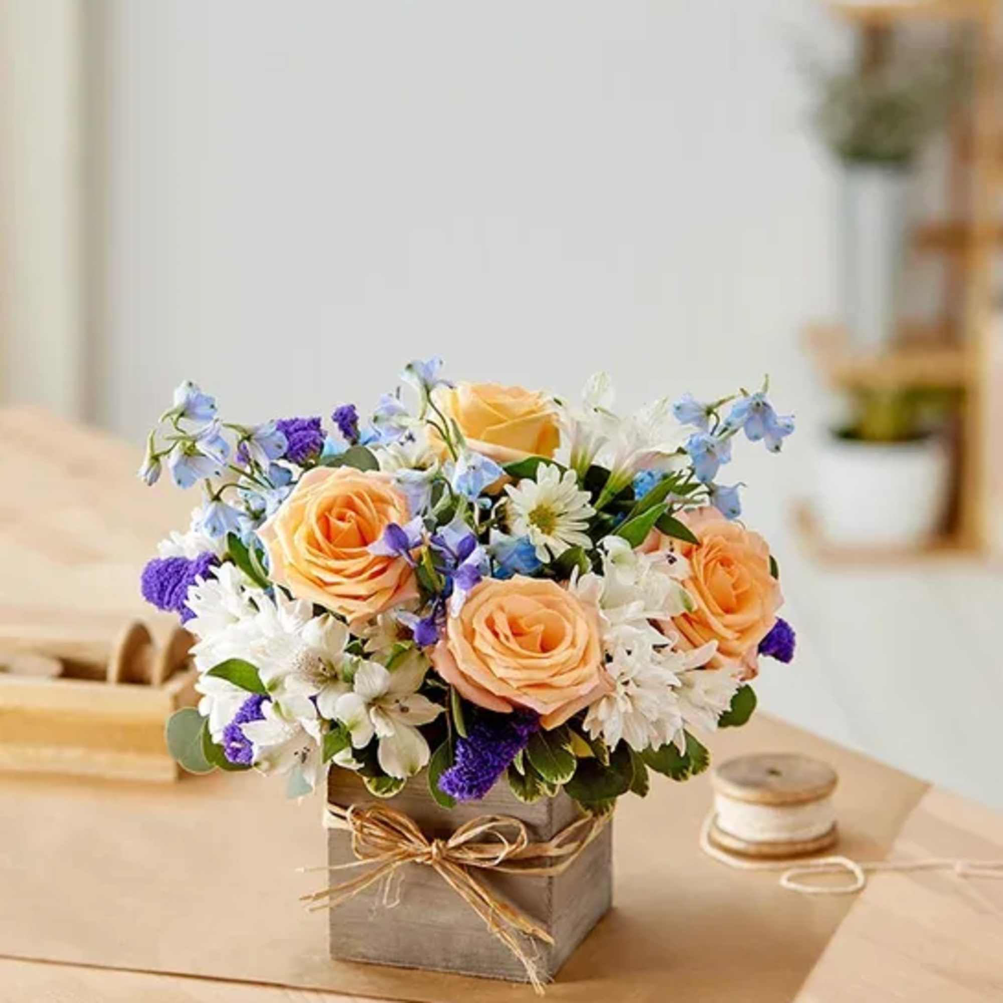 Peach roses and white flowers arranged in a square box