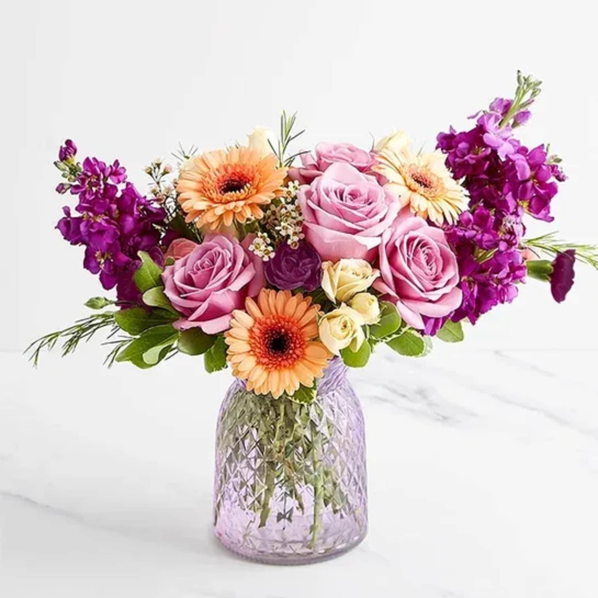 Pink and purple flower bouquet in a textured glass vase