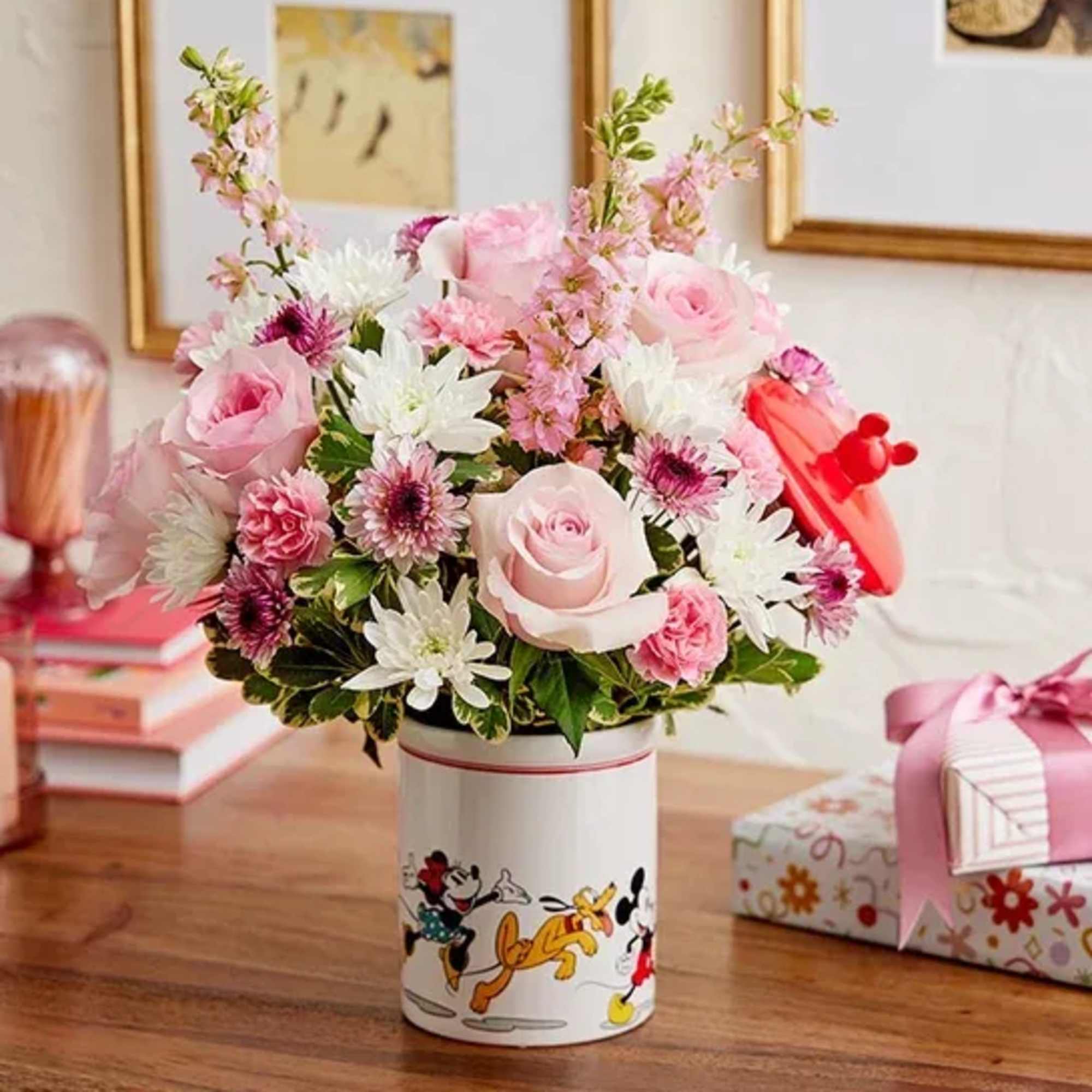 Pink and white flower arrangement in a Disney-themed tin container
