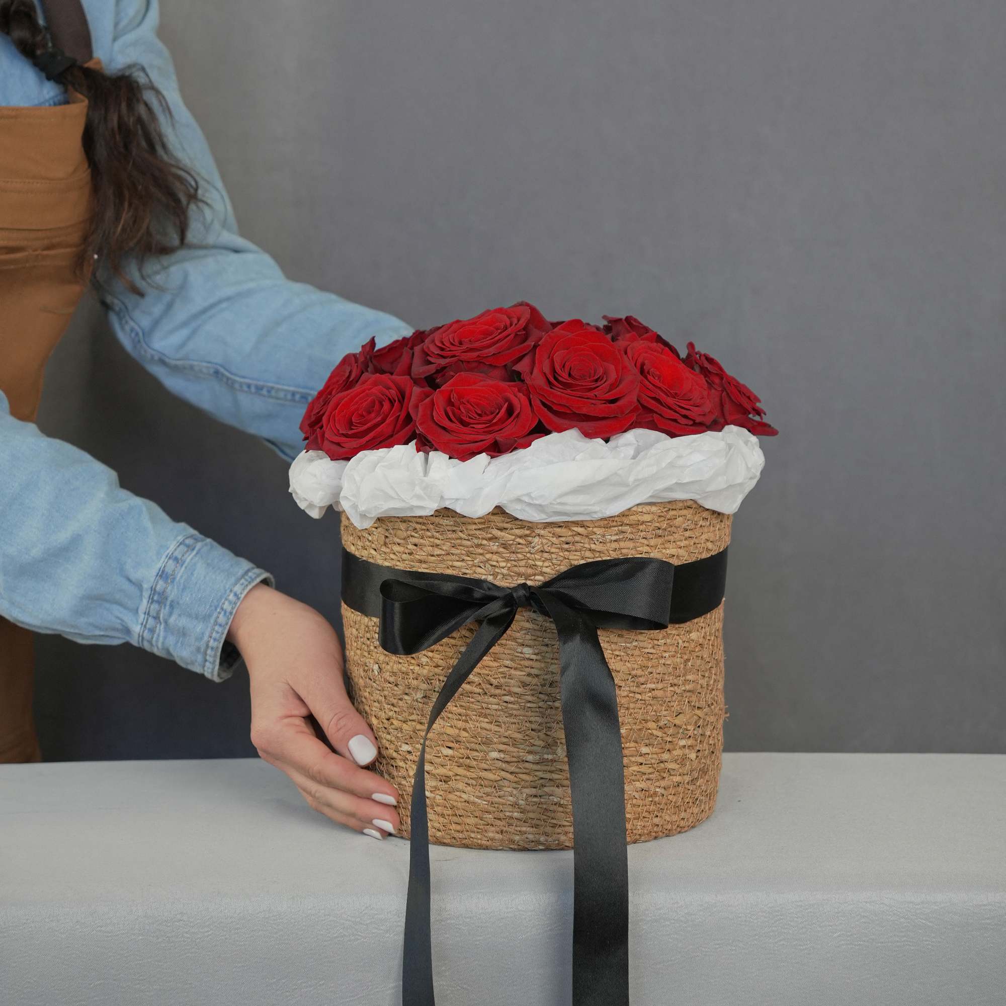 Red roses arranged in a woven hatbox with a black ribbon, photo 2 of 4