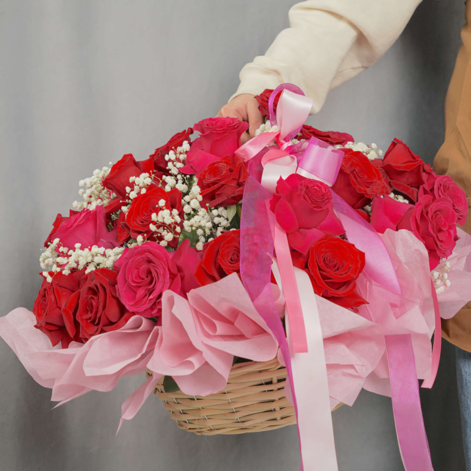 Basket of red and pink roses with baby’s breath and ribbon