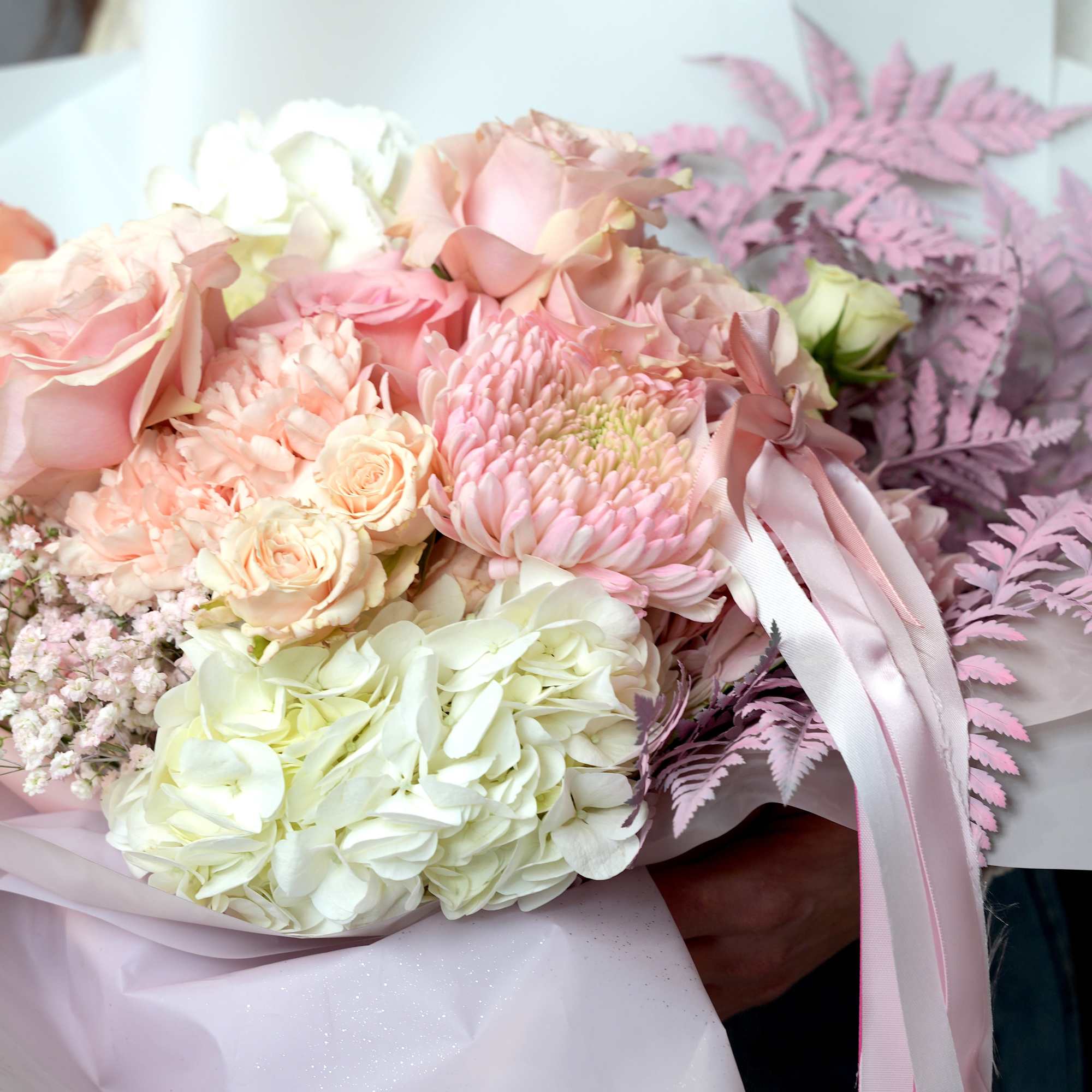 Bouquet of pale pink and white flowers wrapped in pink paper