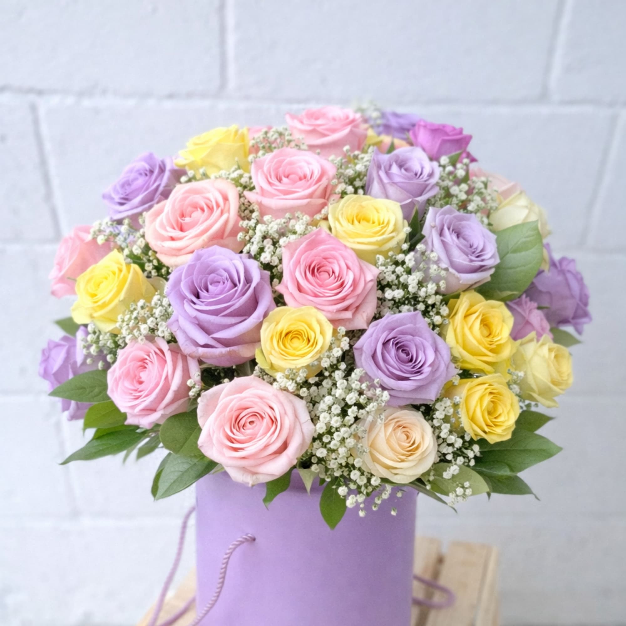 Pastel roses arranged in a lavender hatbox