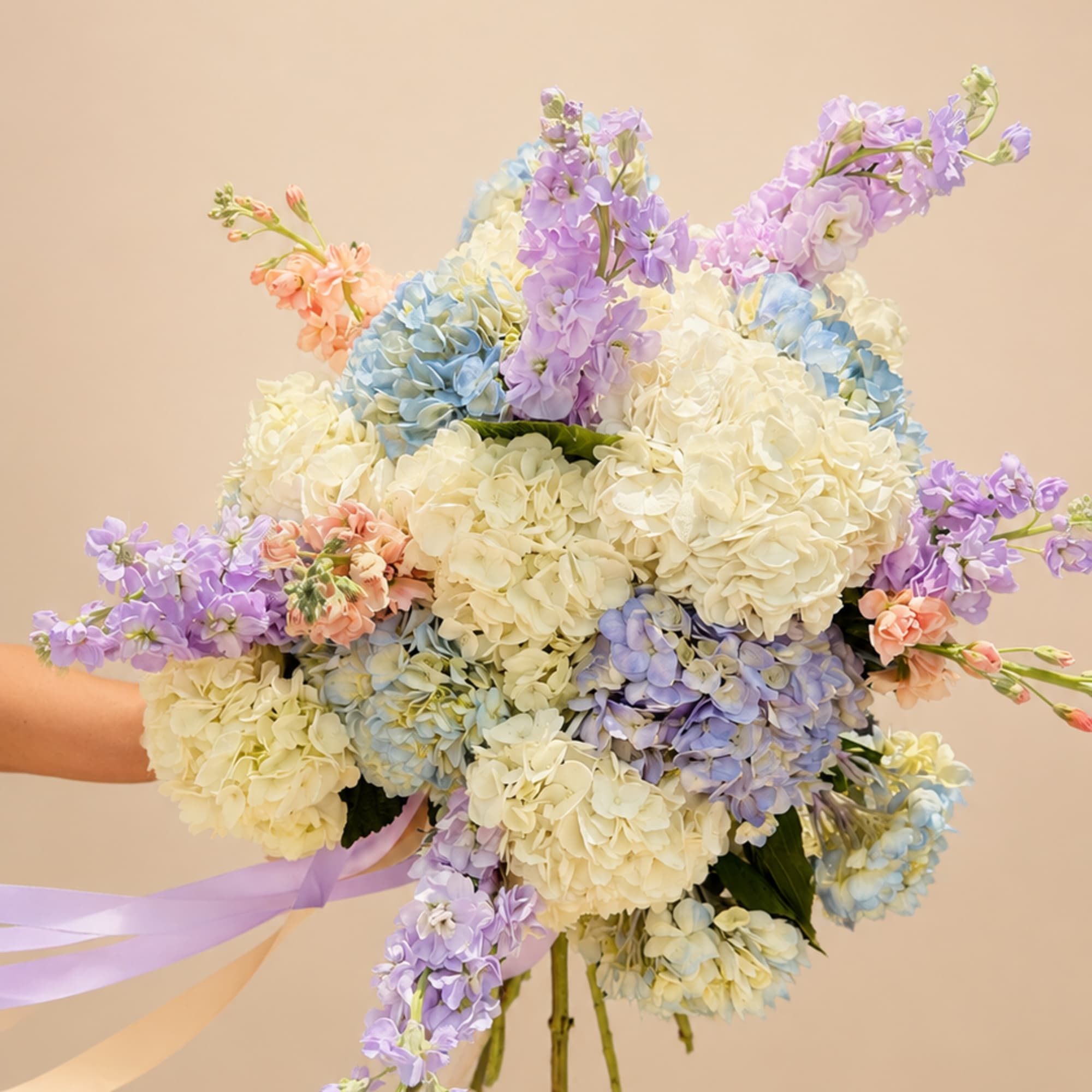 Creamy white hydrangeas take center stage in this large hand-tied bouquet, their