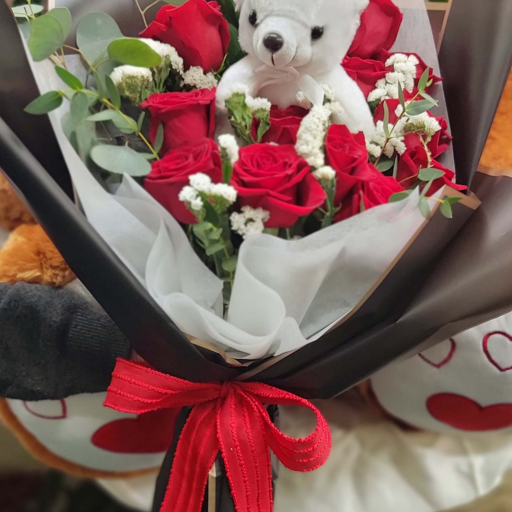 Bouquet of red roses with a white teddy bear and red ribbon