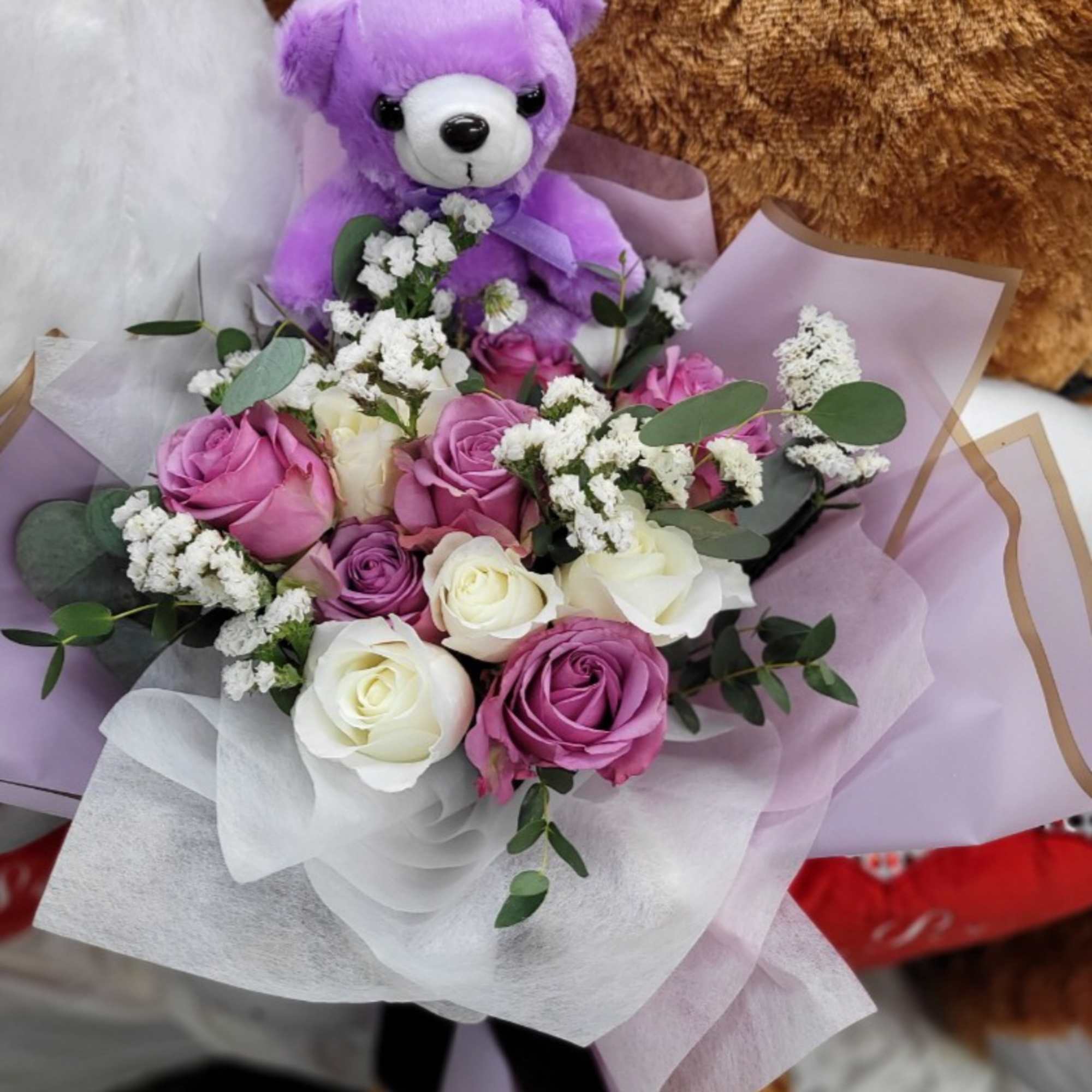 Bouquet of pink and white roses with a purple teddy bear