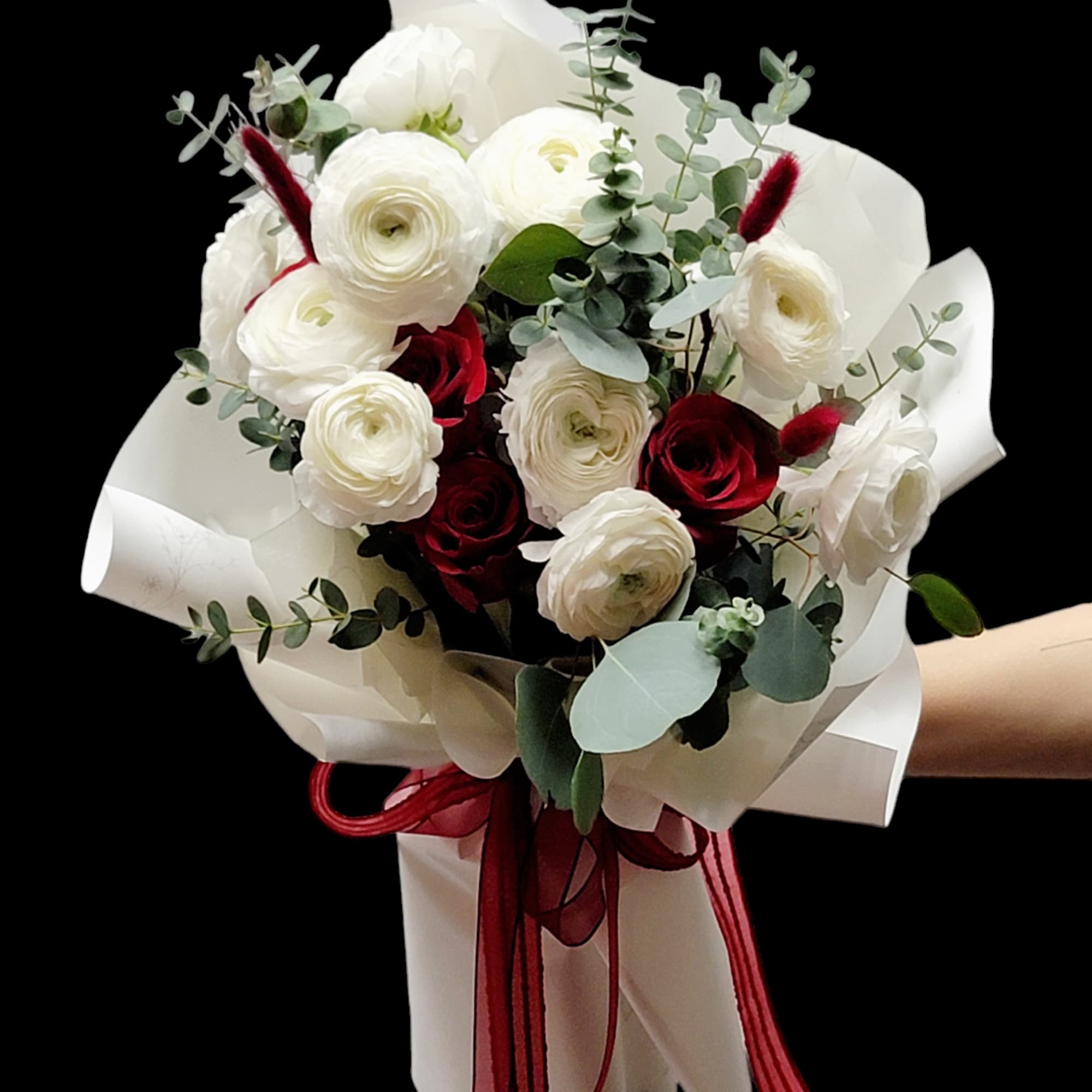 Bouquet of white and deep red flowers wrapped in white paper with a red ribbon
