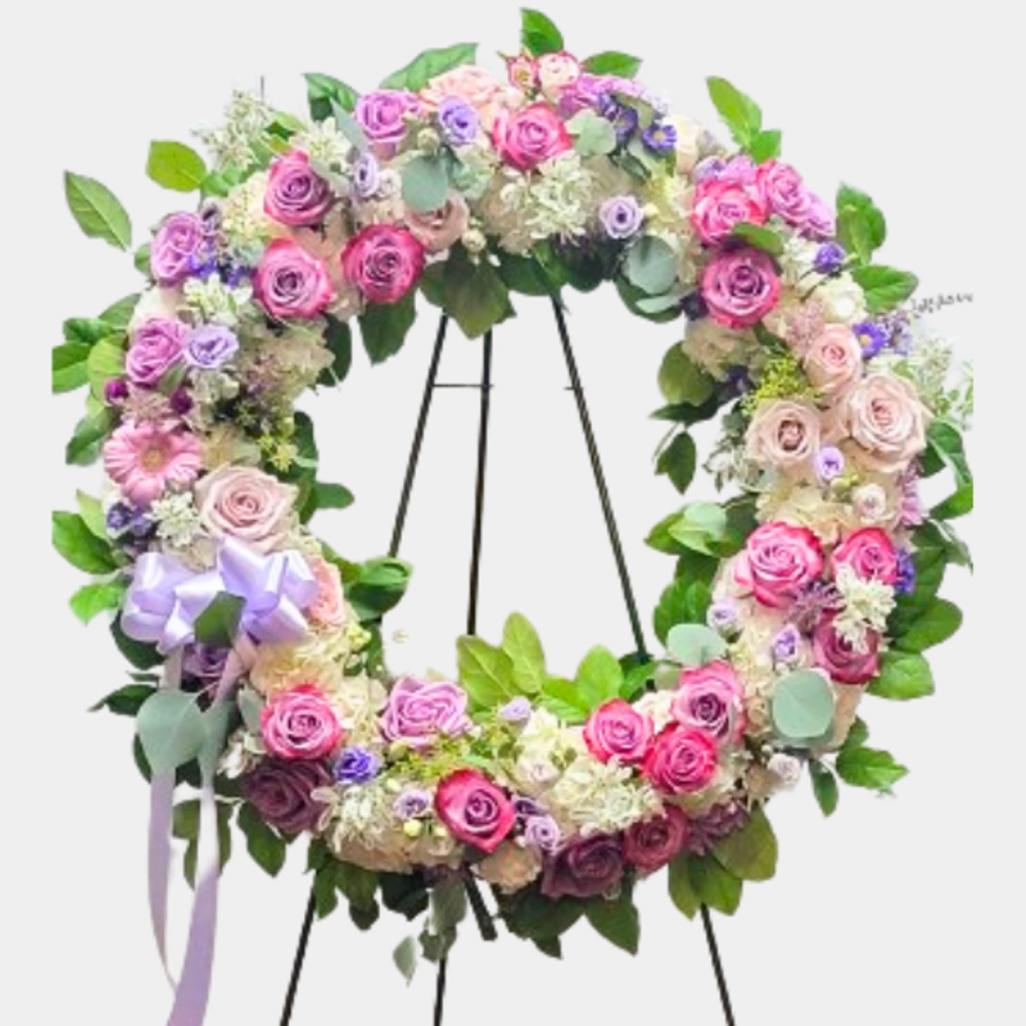 Circular floral wreath with pink and purple roses on a stand
