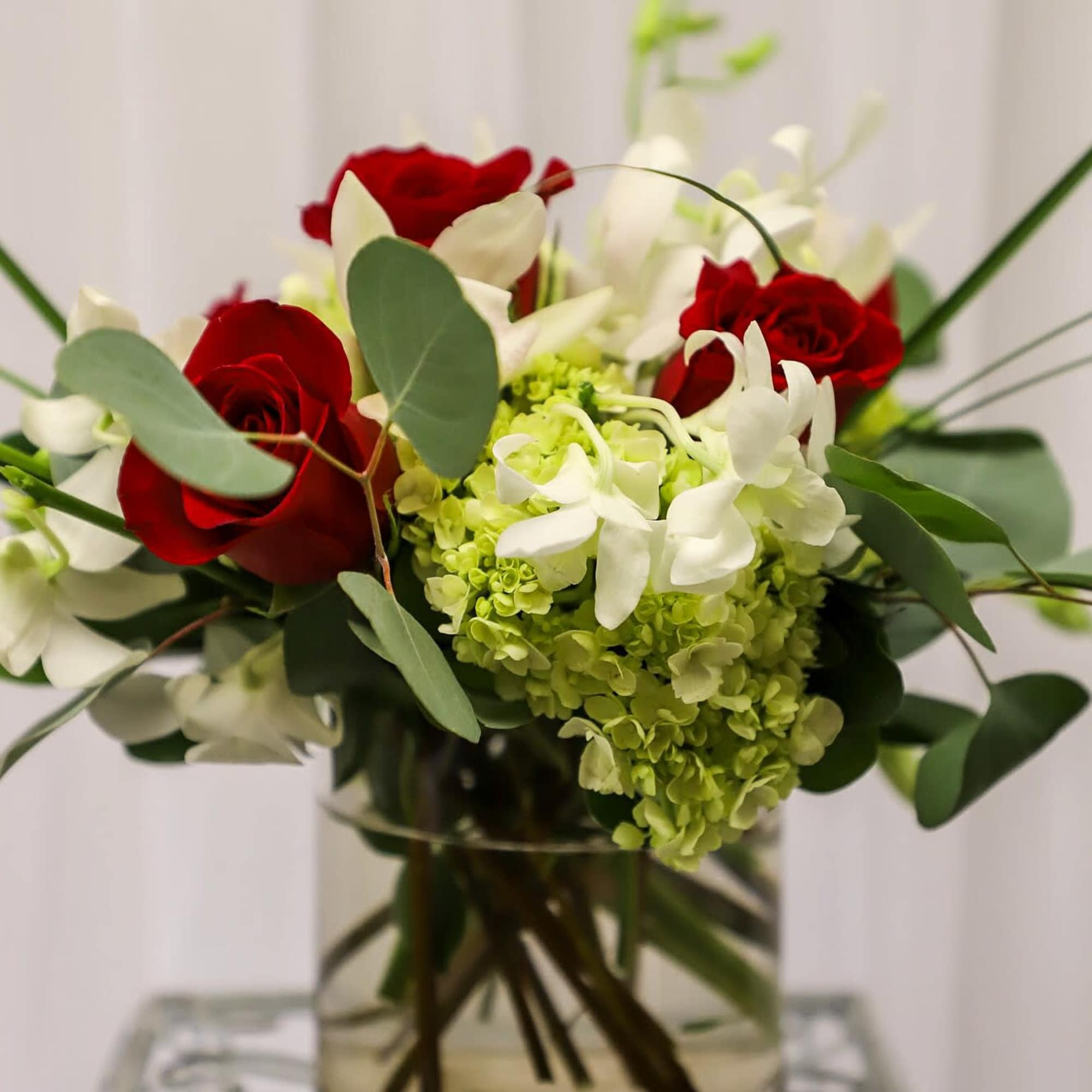 Red roses and white flowers arranged in a clear glass vase