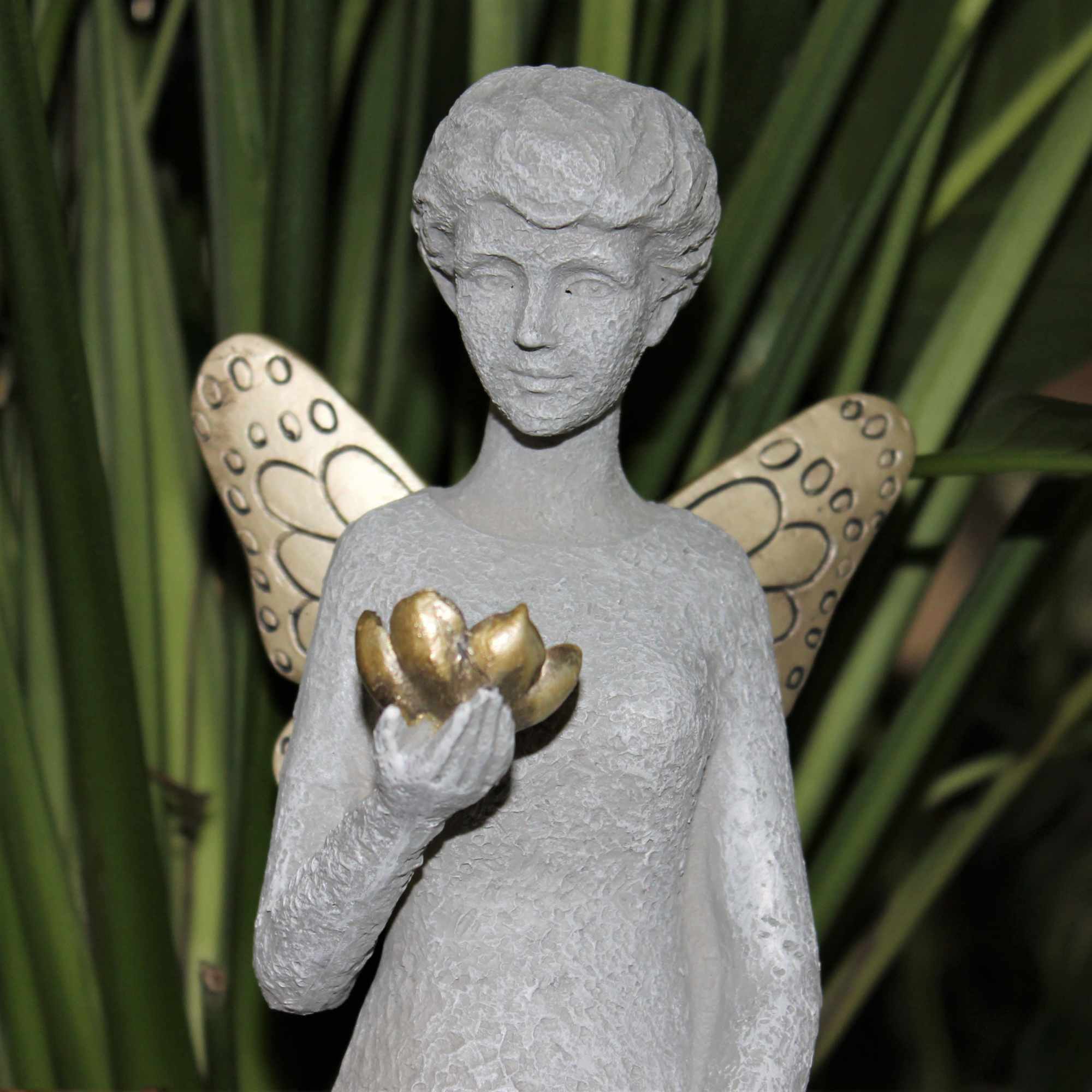 Gray fairy figurine holding a gold flower with patterned wings