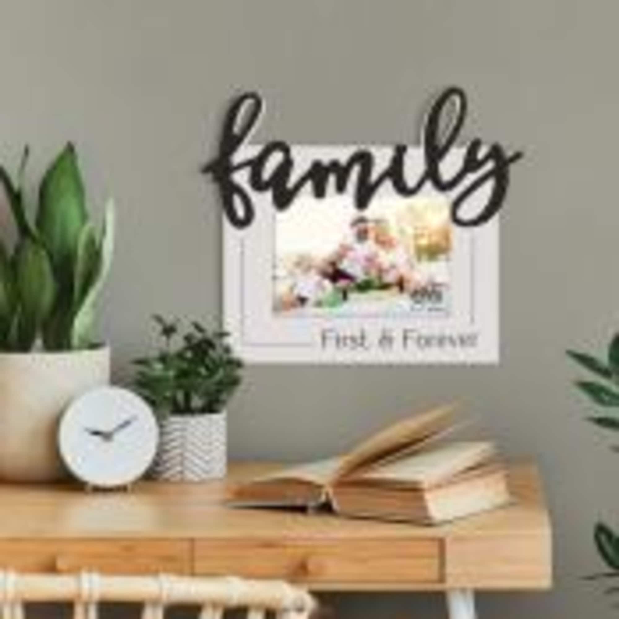Wall art above a desk with potted plants and an open book