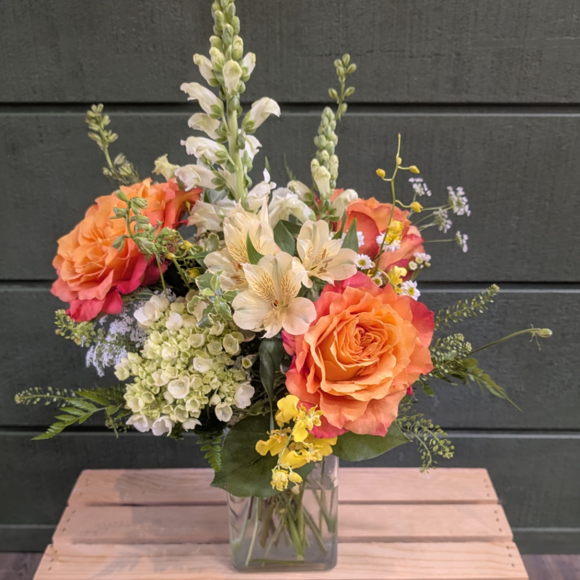 Orange and pink bouquet with roses, alstroemeria, and white snapdragons in a glass vase
