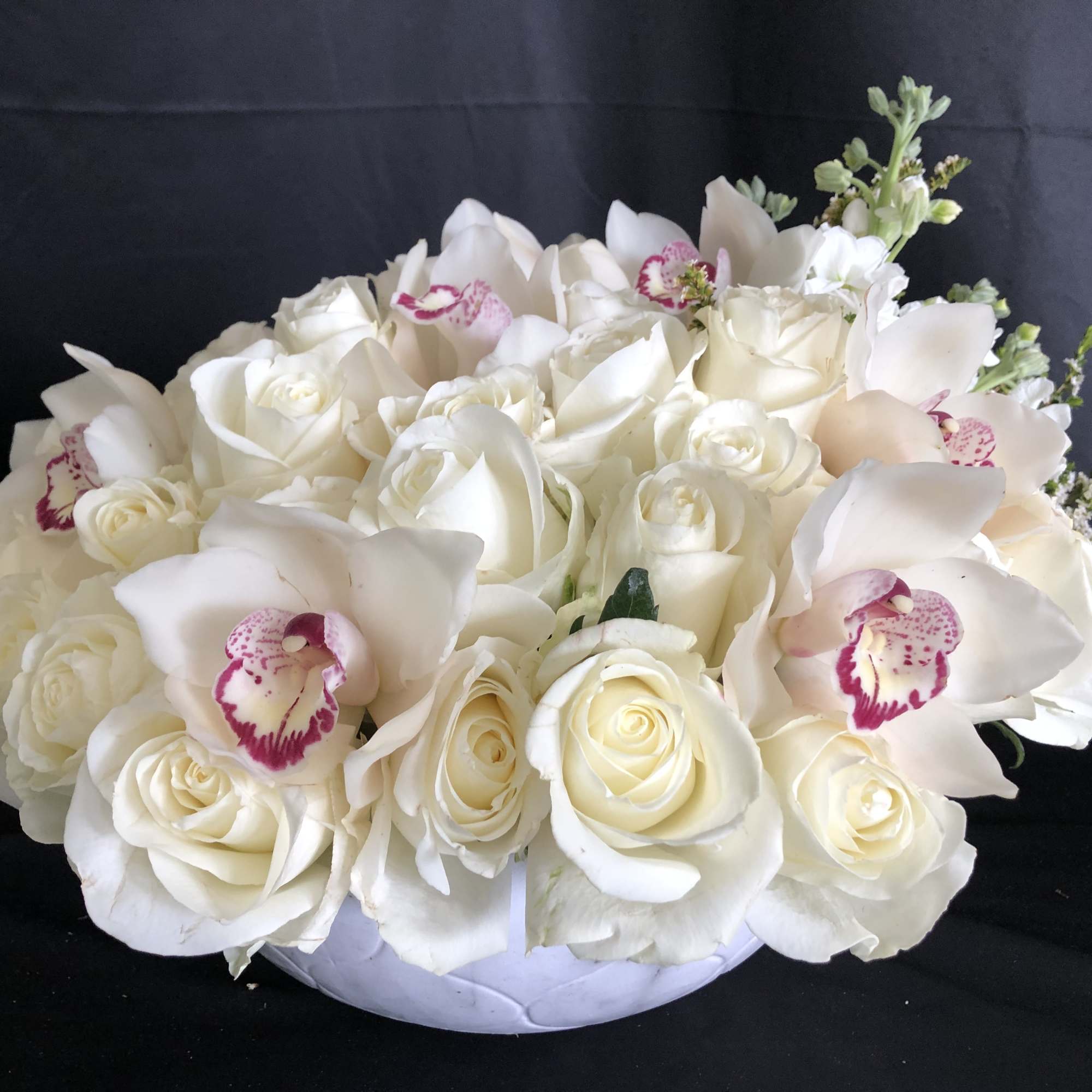 White rose and orchid arrangement in a low white bowl
