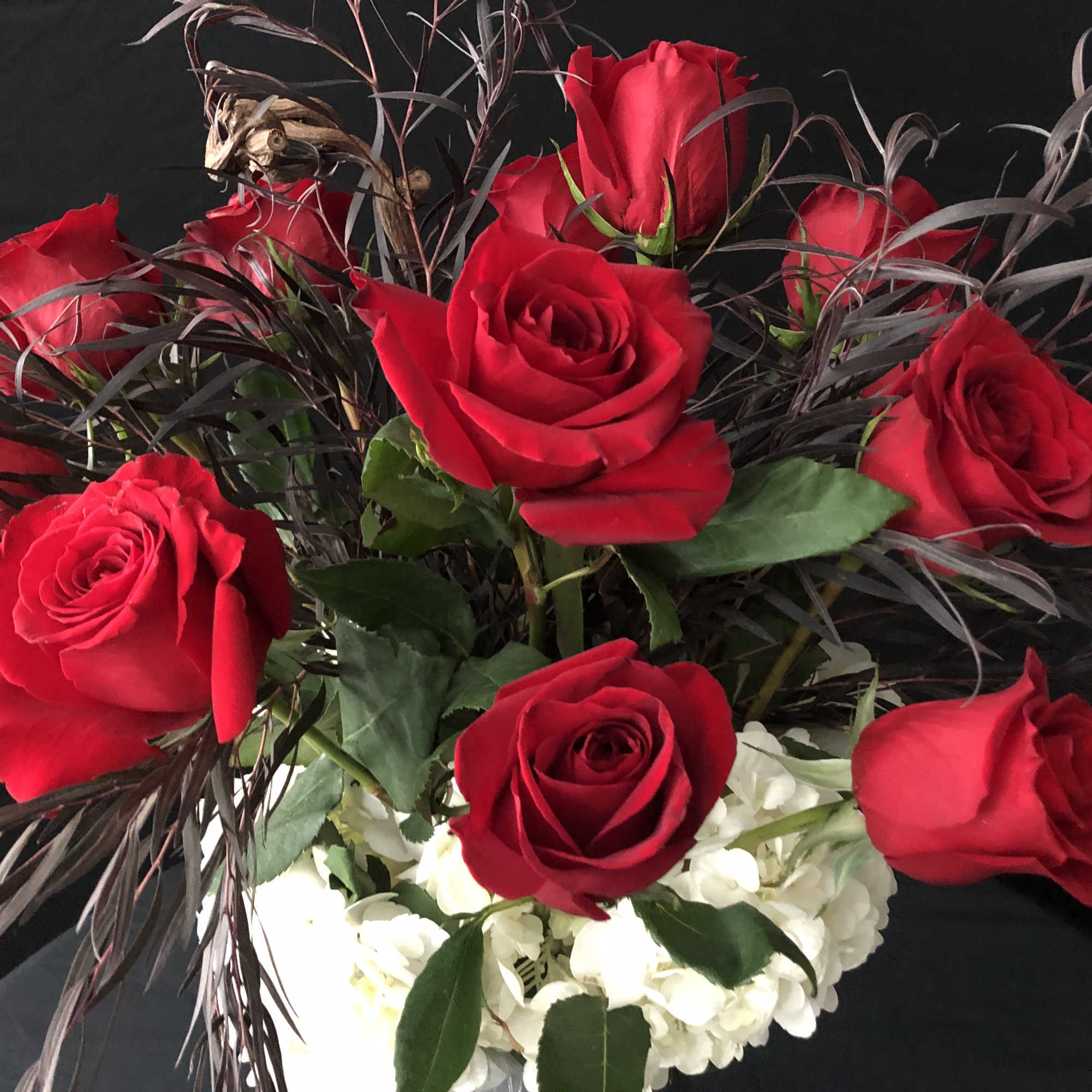 Red roses arranged with white hydrangeas in a vase