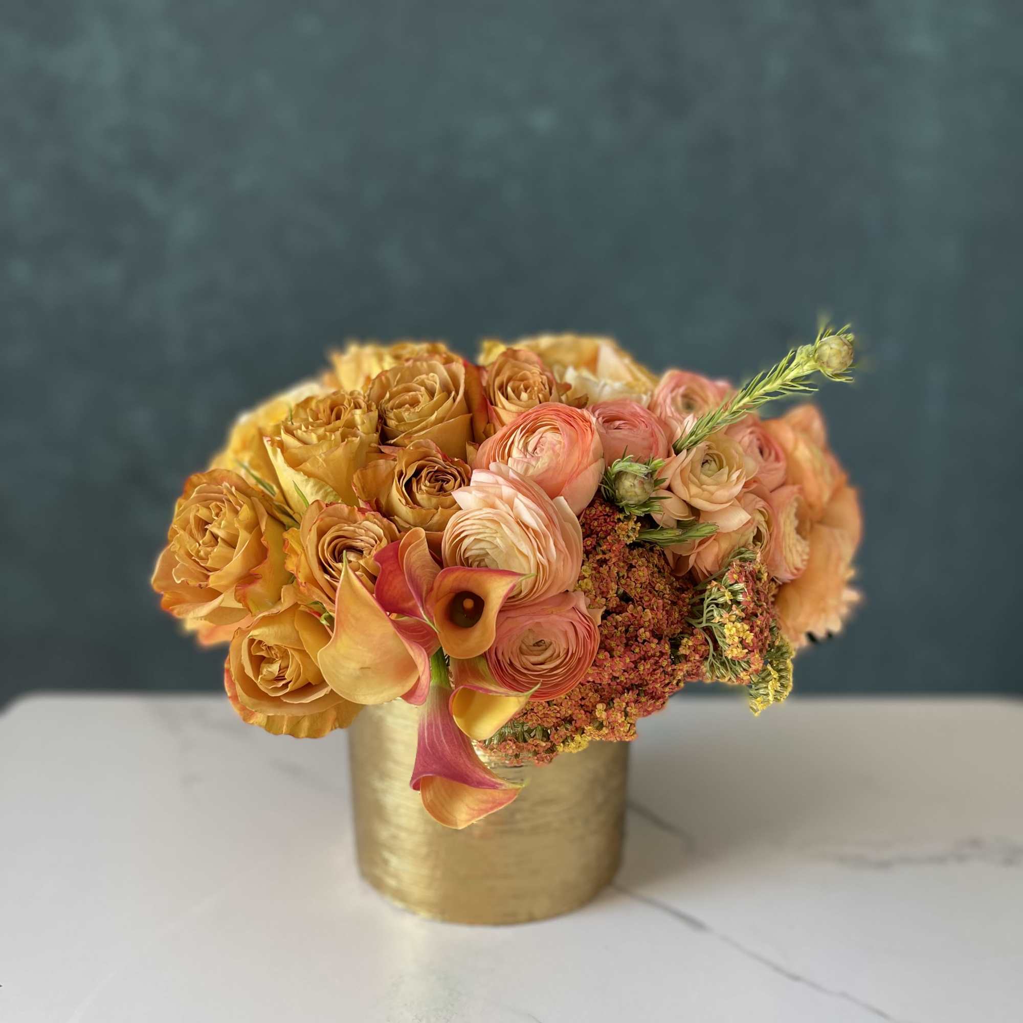 Gold like roses, peach ranunculus, callas and mango callas with greenery. 
