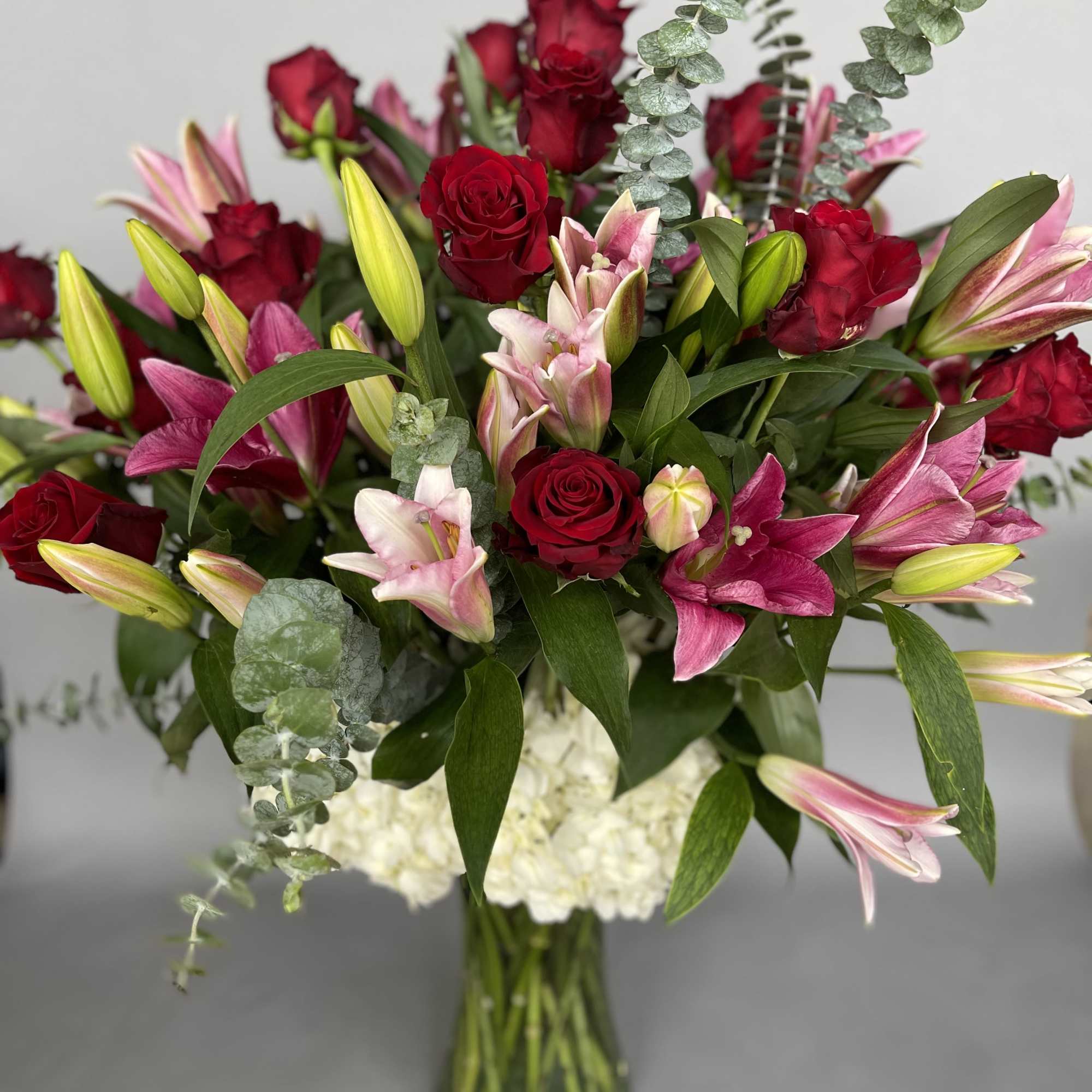Bouquet of red roses and pink lilies in a glass vase