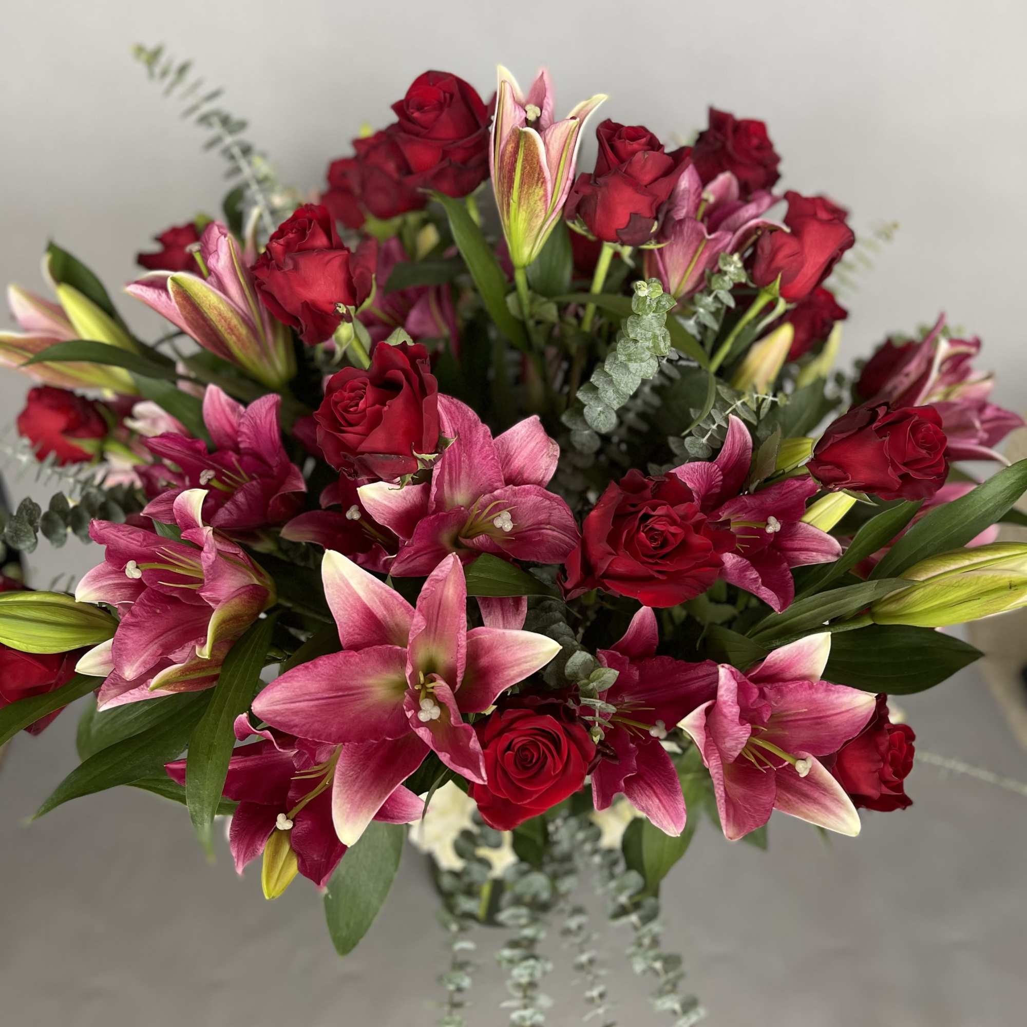 Bouquet of red roses and pink lilies with trailing greenery