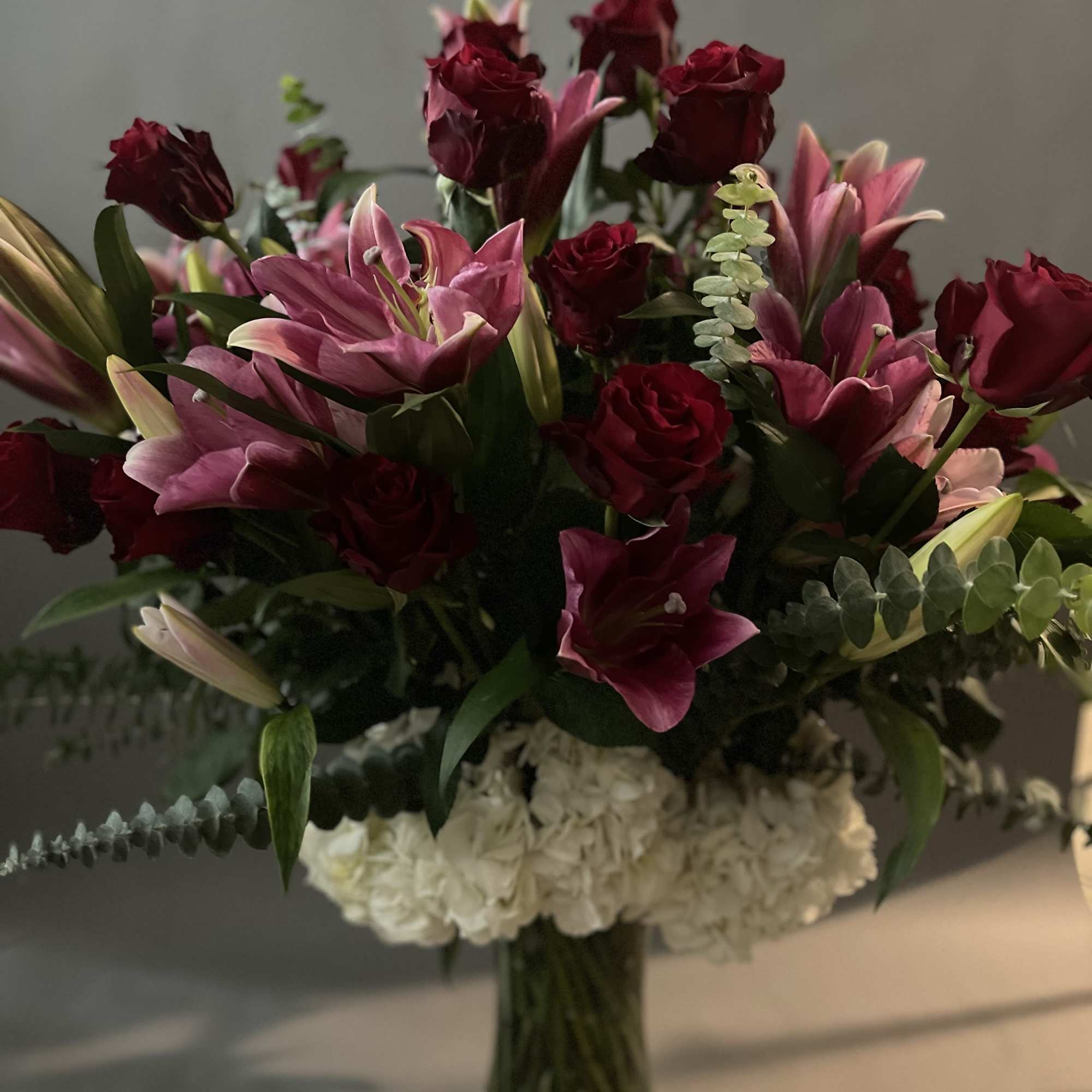 Bouquet of burgundy roses and pink lilies in a glass vase