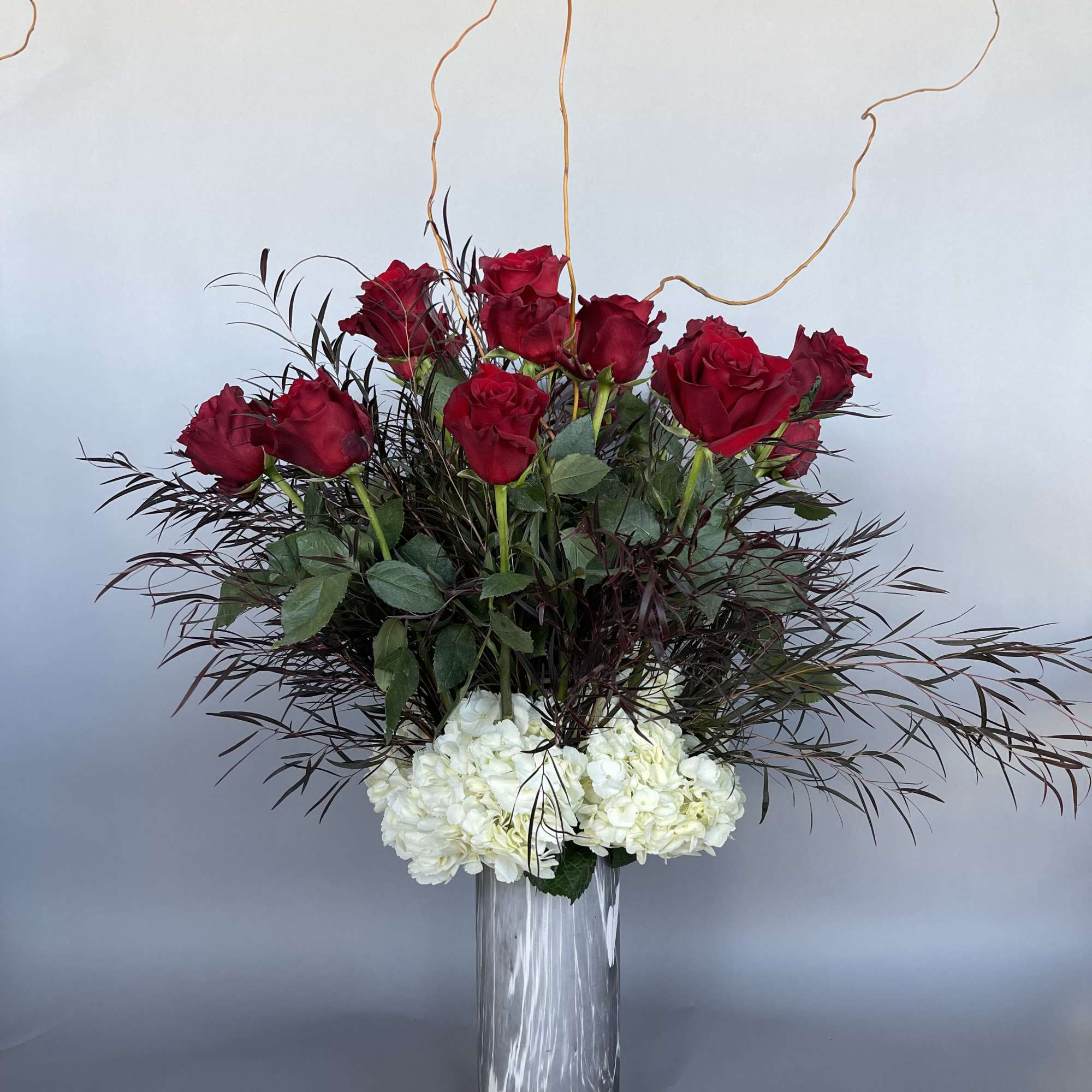 Red roses and white hydrangeas in a tall glass vase