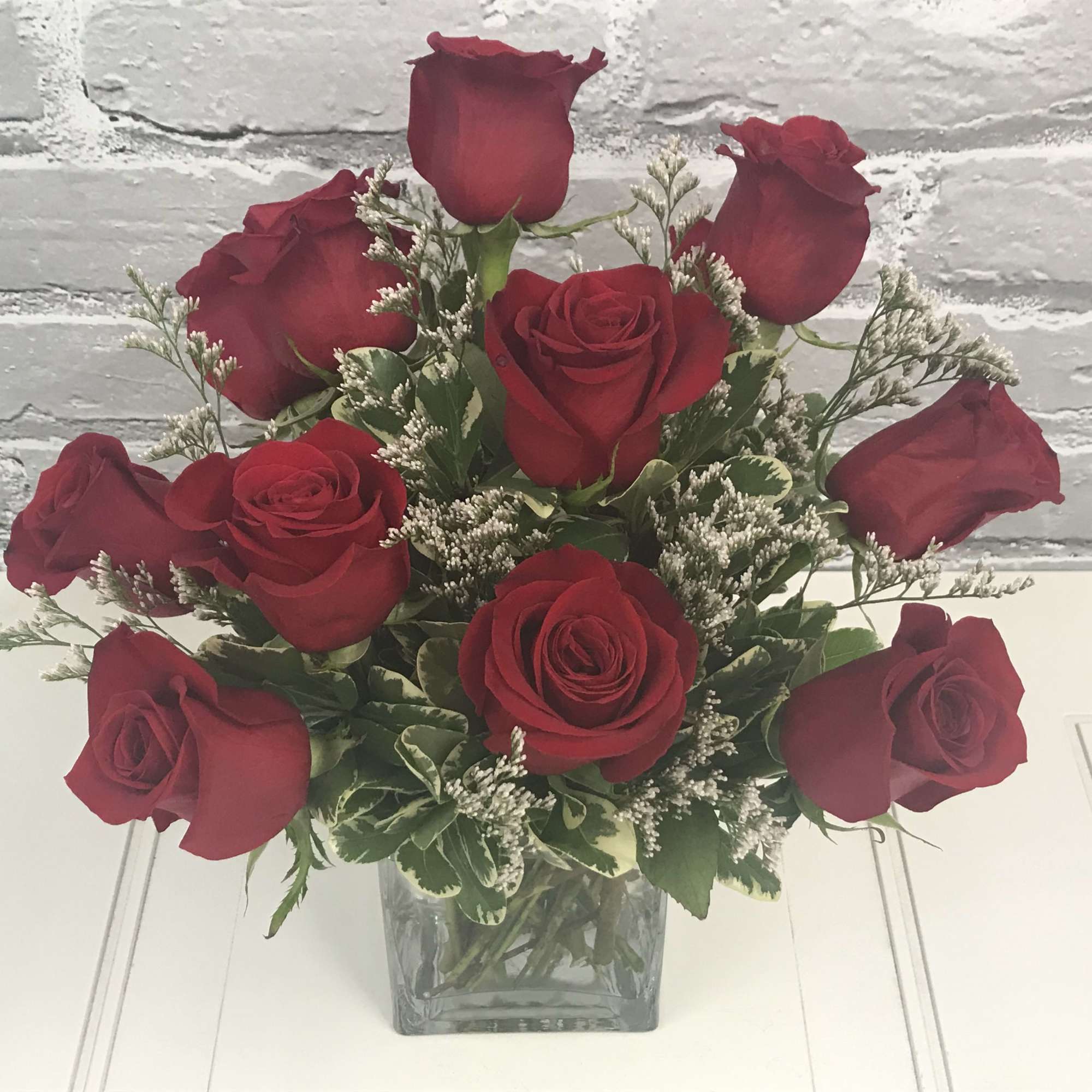 Red roses arranged in a clear square glass vase