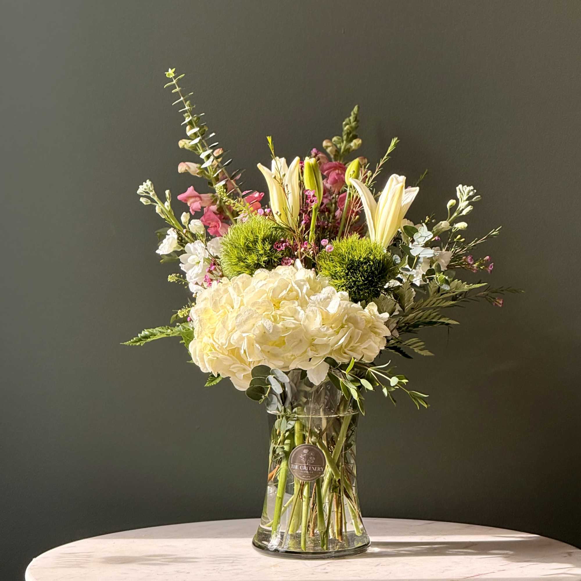 Beautiful floral arrangement in a clear vase with lilies, hydrangeas, snapdragon, green